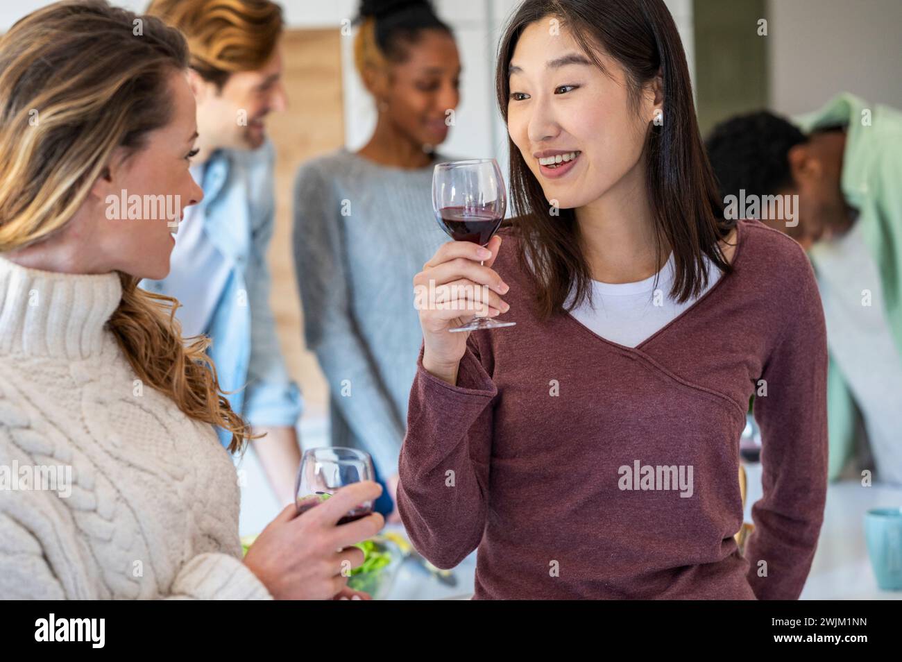 Two friends talking during reunion while drinking wine Stock Photo