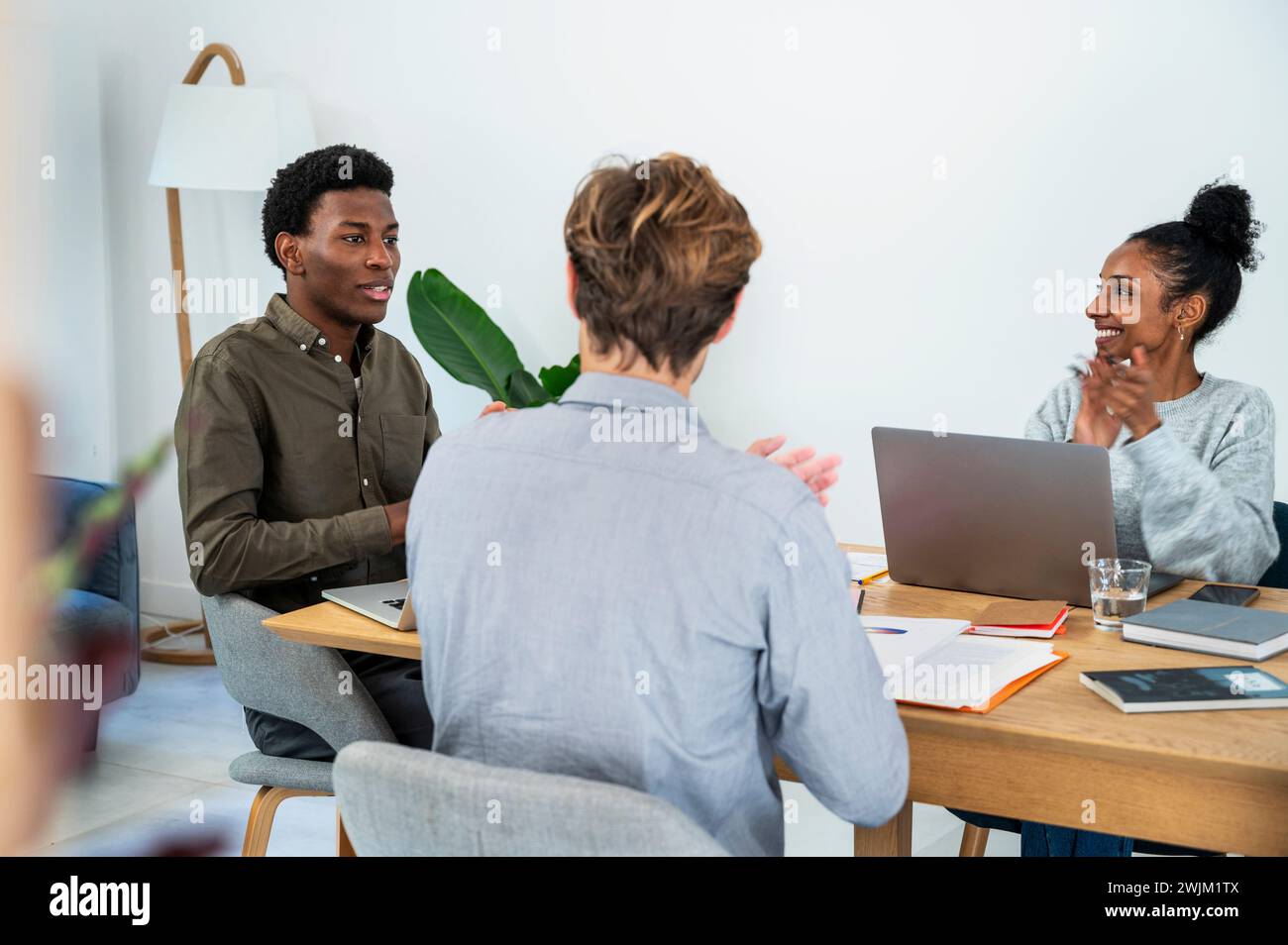 Businessman talking with colleagues while they are clapping hands Stock Photo
