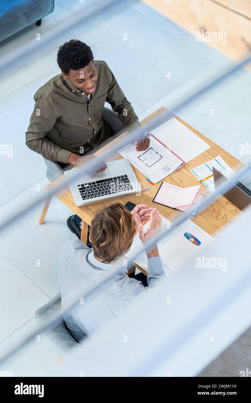 Businessmen discussing work while at desk using laptop Stock Photo