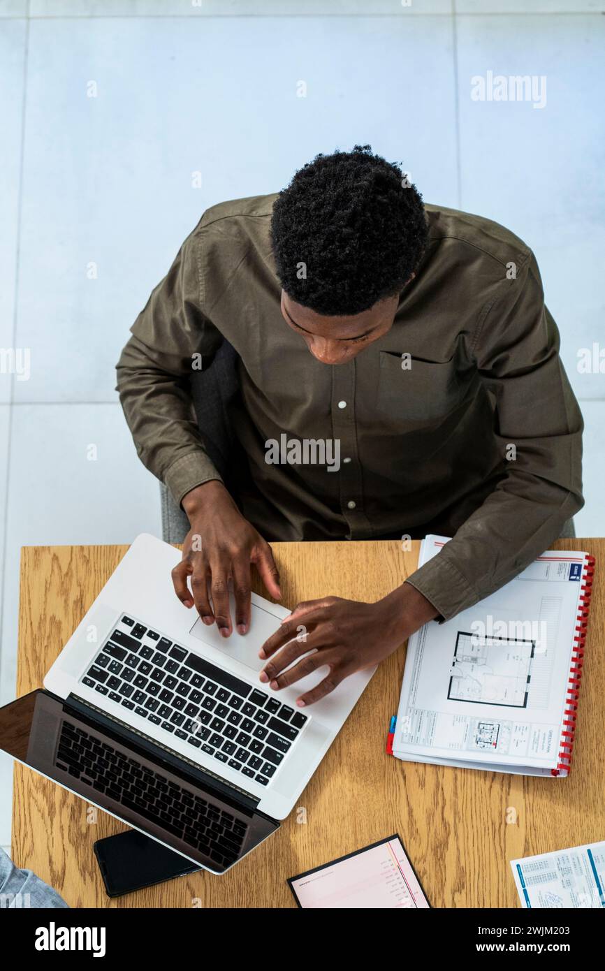 Advertising agency worker using laptop while sitting at desk Stock Photo