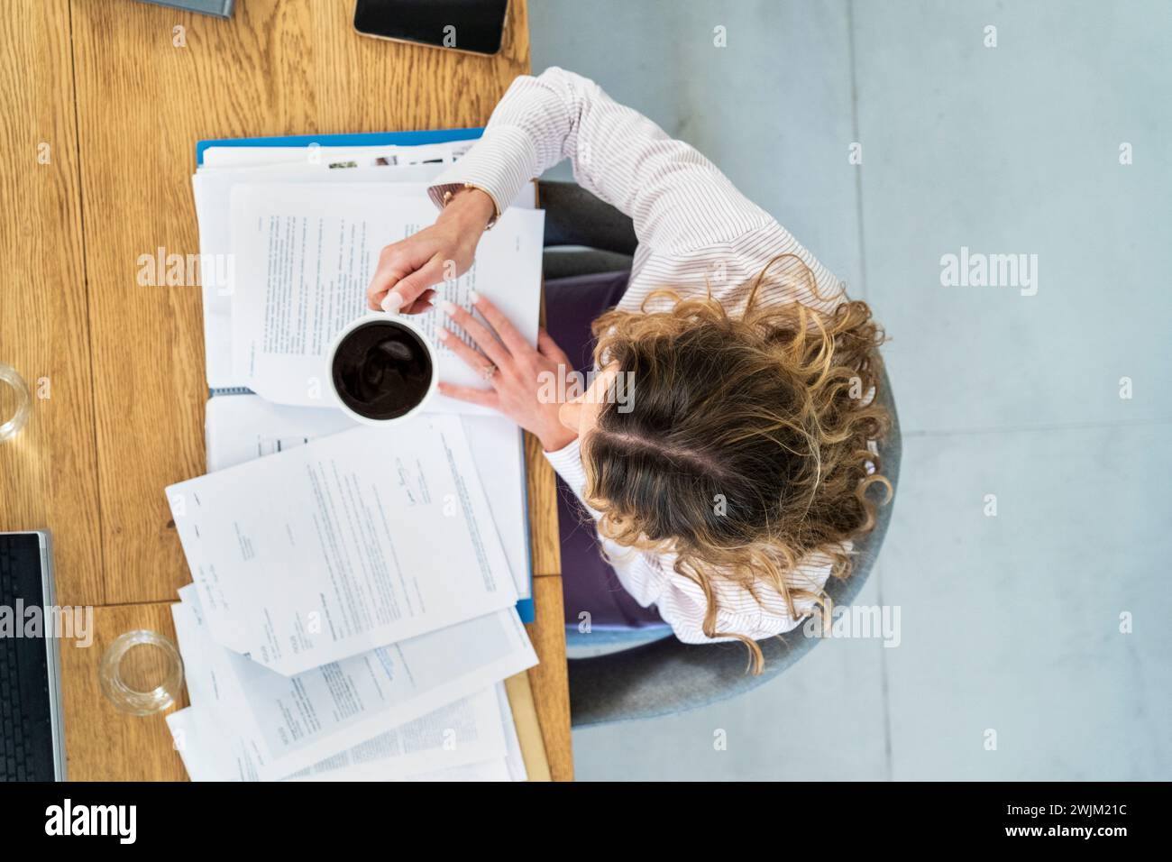 Advertising agency worker drinking coffee while doing paper work Stock Photo