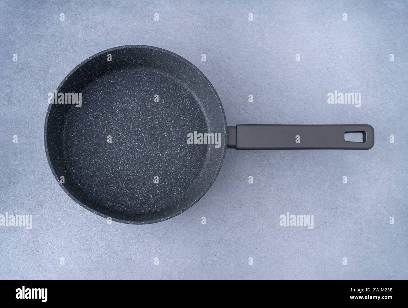 New granite frying pan on a gray background, top view. Empty fry pan with handle Stock Photo