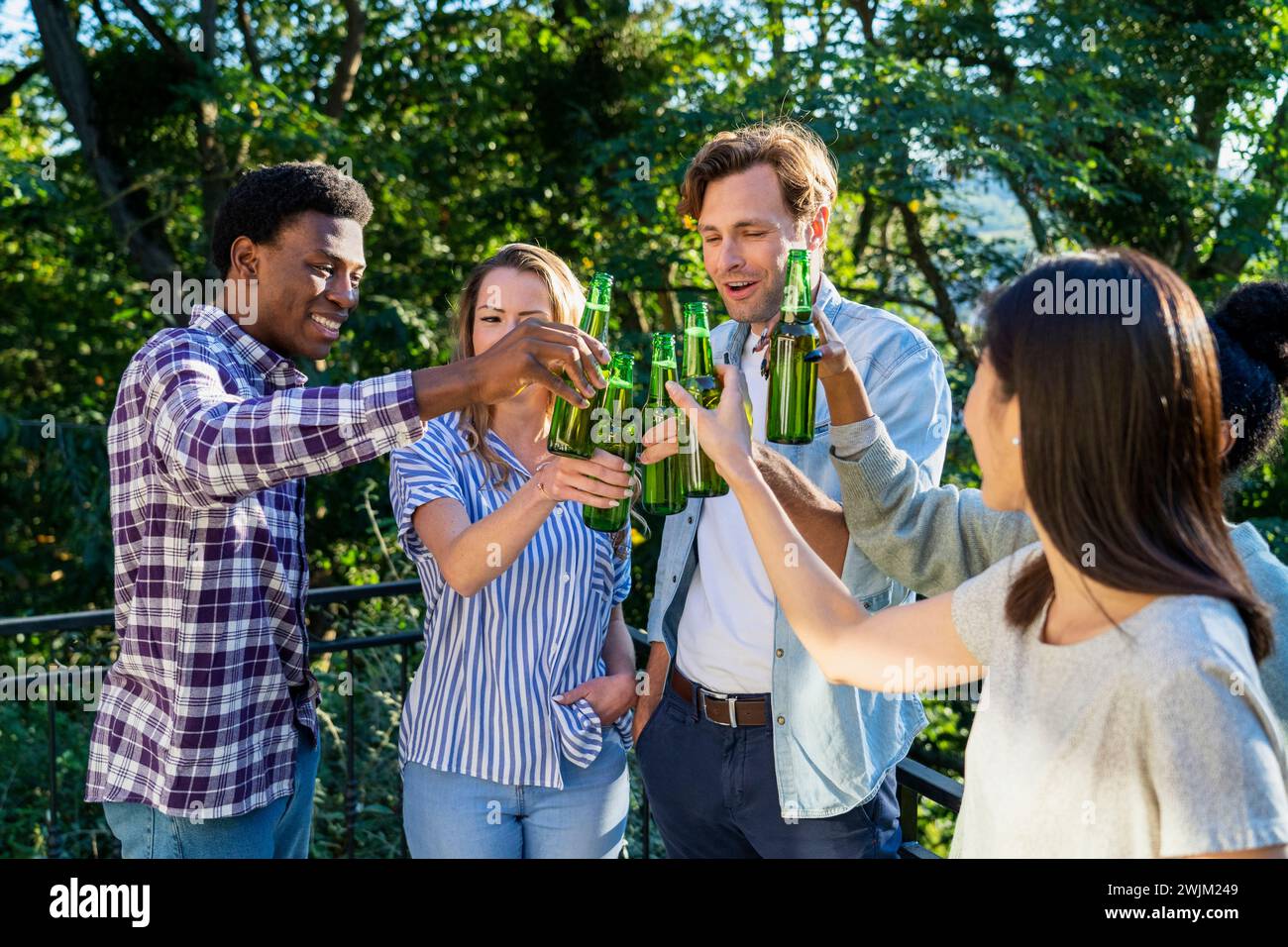 Group of friends toasting with beer bottles standing outdoors Stock Photo
