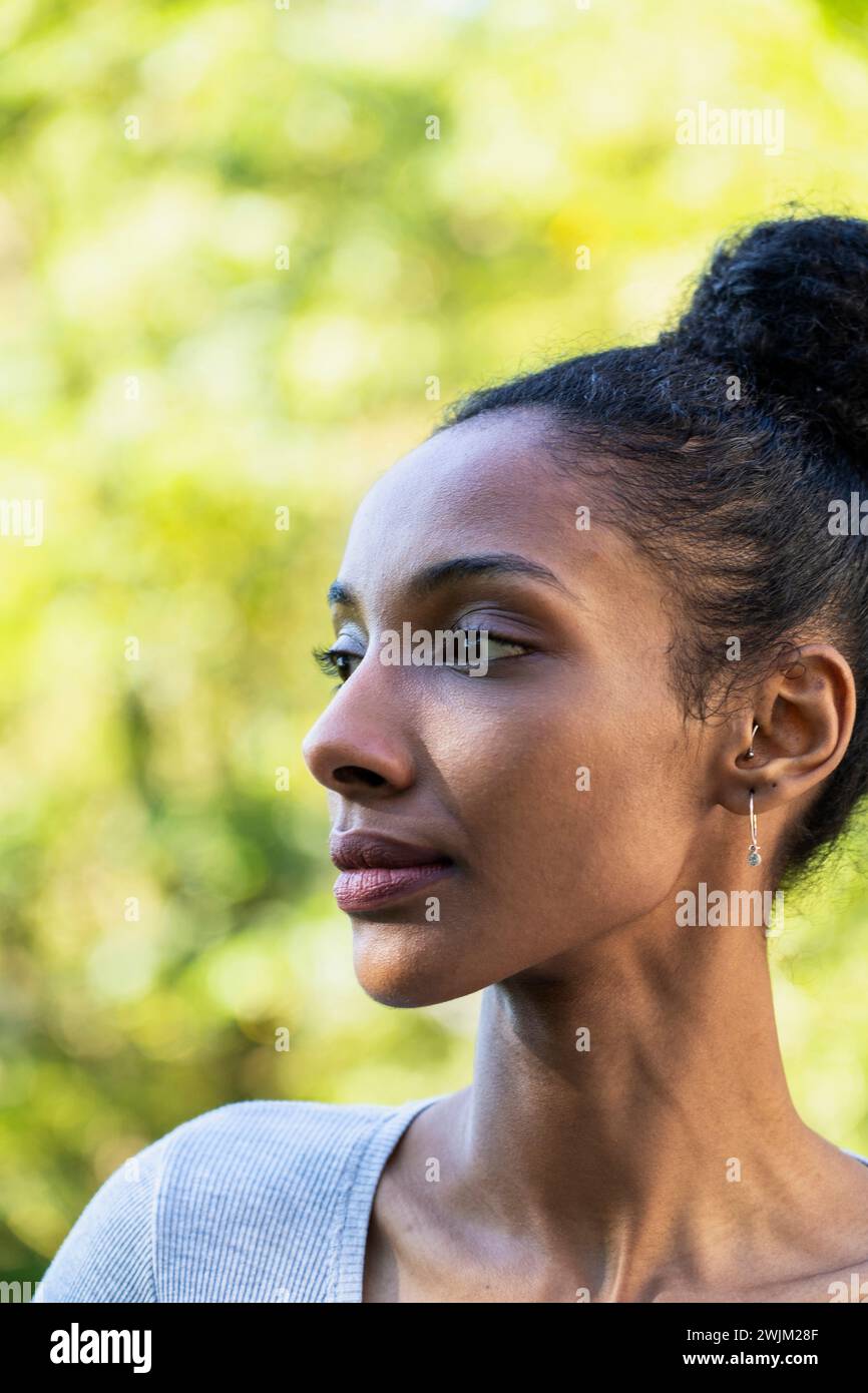 Side view portrait of young adult woman looking to the side standing outdoors Stock Photo