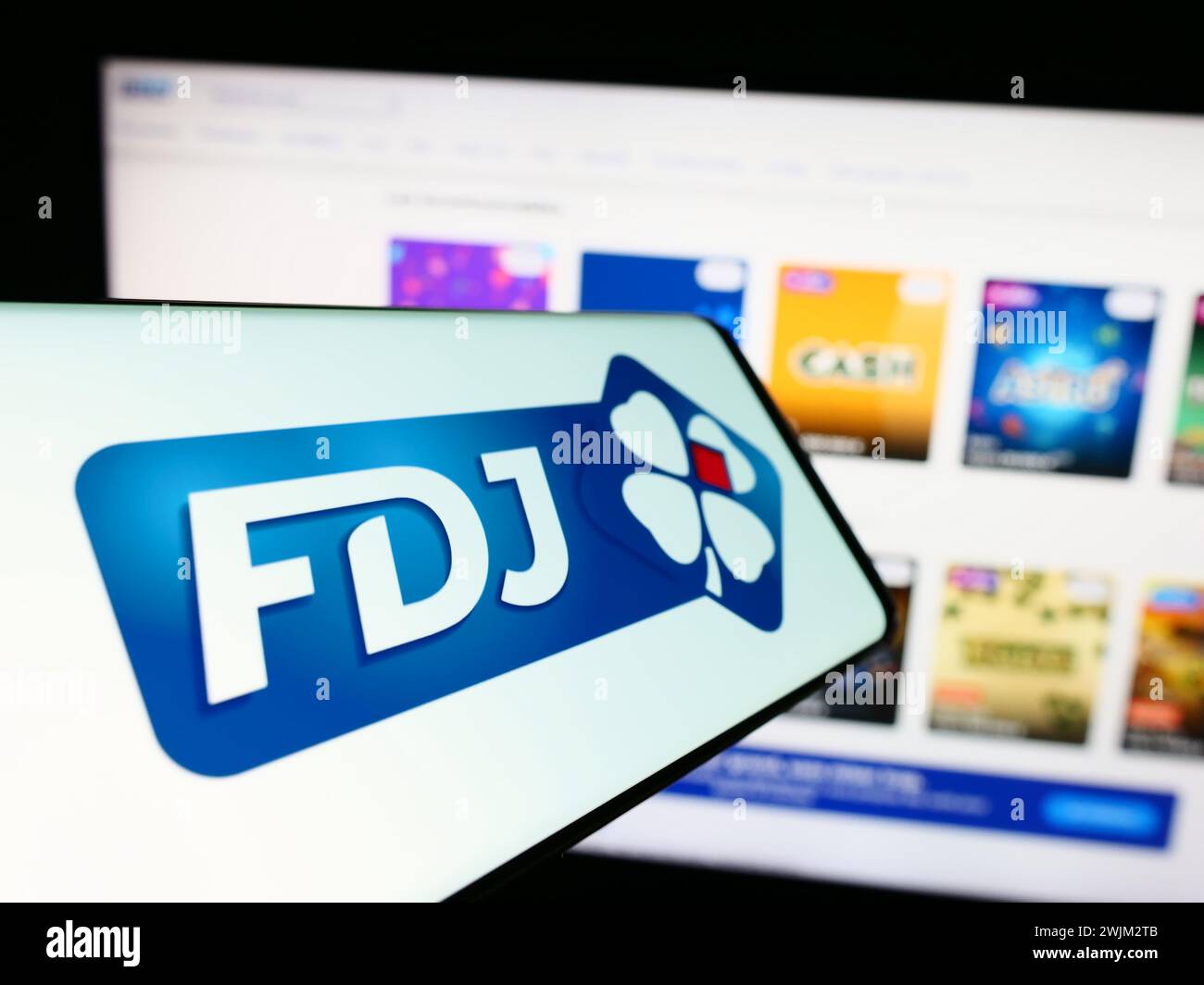 Mobile phone with logo of French lottery company Francaise des Jeux (FDJ) in front of business website. Focus on center of phone display. Stock Photo