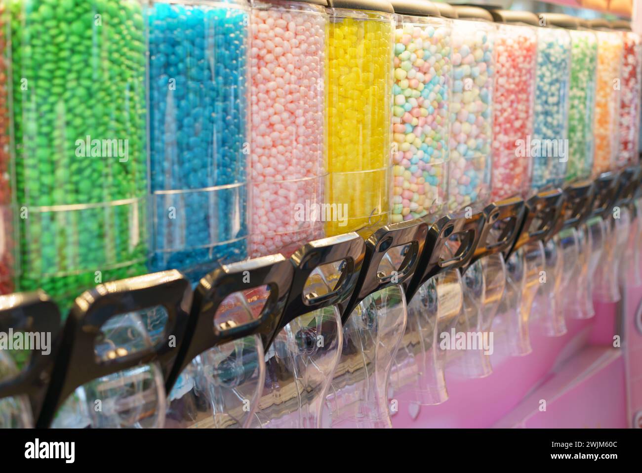 A vibrant display of candy dispensers filled with a variety of colorful sweets, offering a delightful choice for those with a sweet tooth Stock Photo