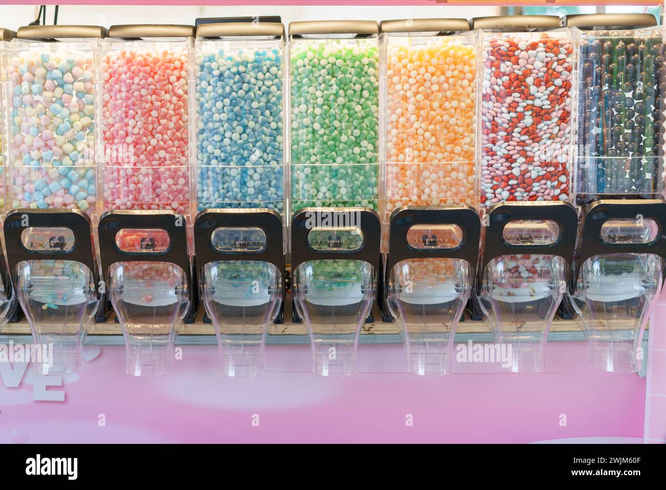 A vibrant display of candy dispensers filled with a variety of colorful sweets, offering a delightful choice for those with a sweet tooth Stock Photo