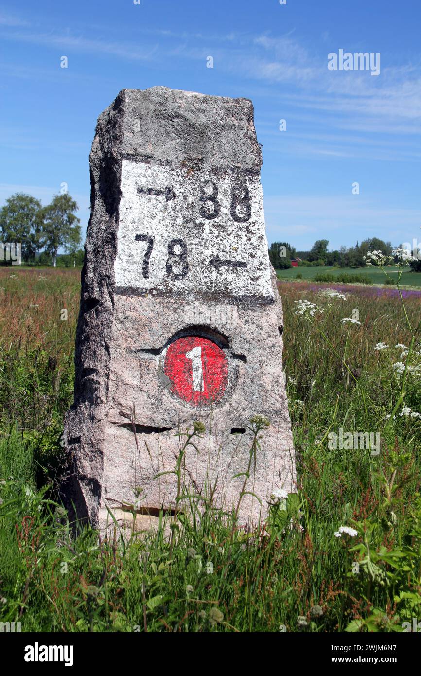 Old milestone made of granite by Highway 110 (Previously number 1) in Kitula, Finland with summer landscape. Stock Photo