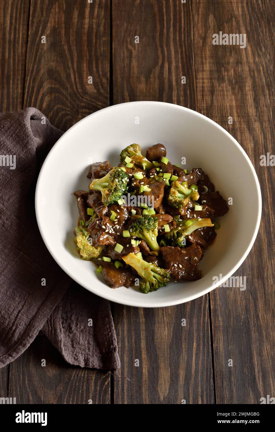 Beef with broccoli in bowl on wooden background. Thinly sliced beef meat with roasted broccoli. Close up view Stock Photo