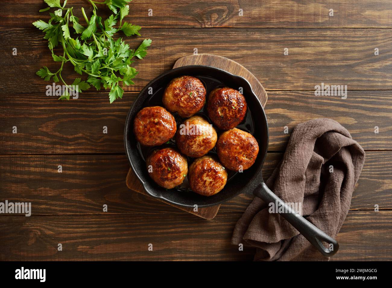 Minced pork and beef cutlets in cast iron skillet over wooden background. Top view, flat lay Stock Photo