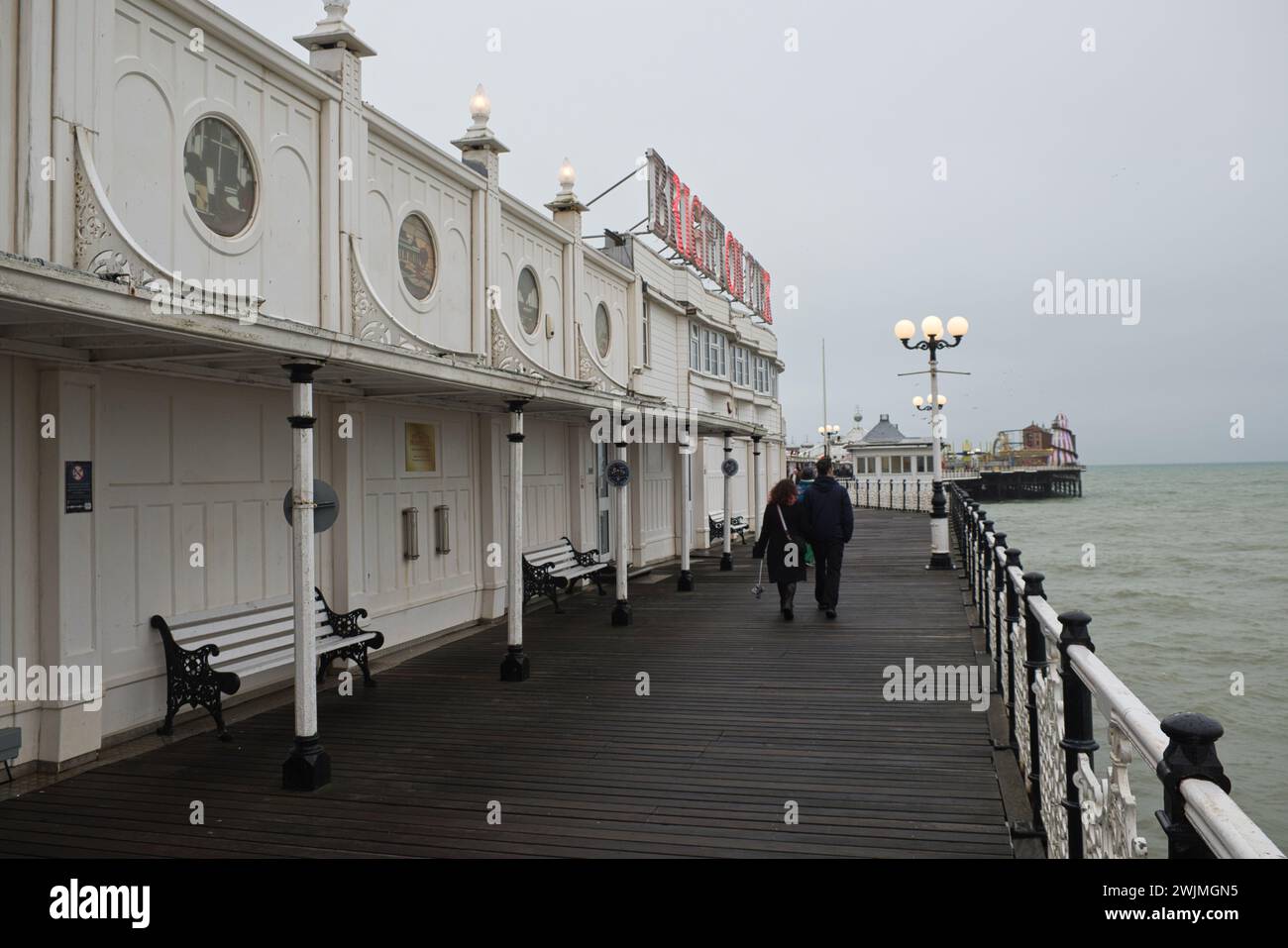 young couple walk along bright pier in winter Stock Photo
