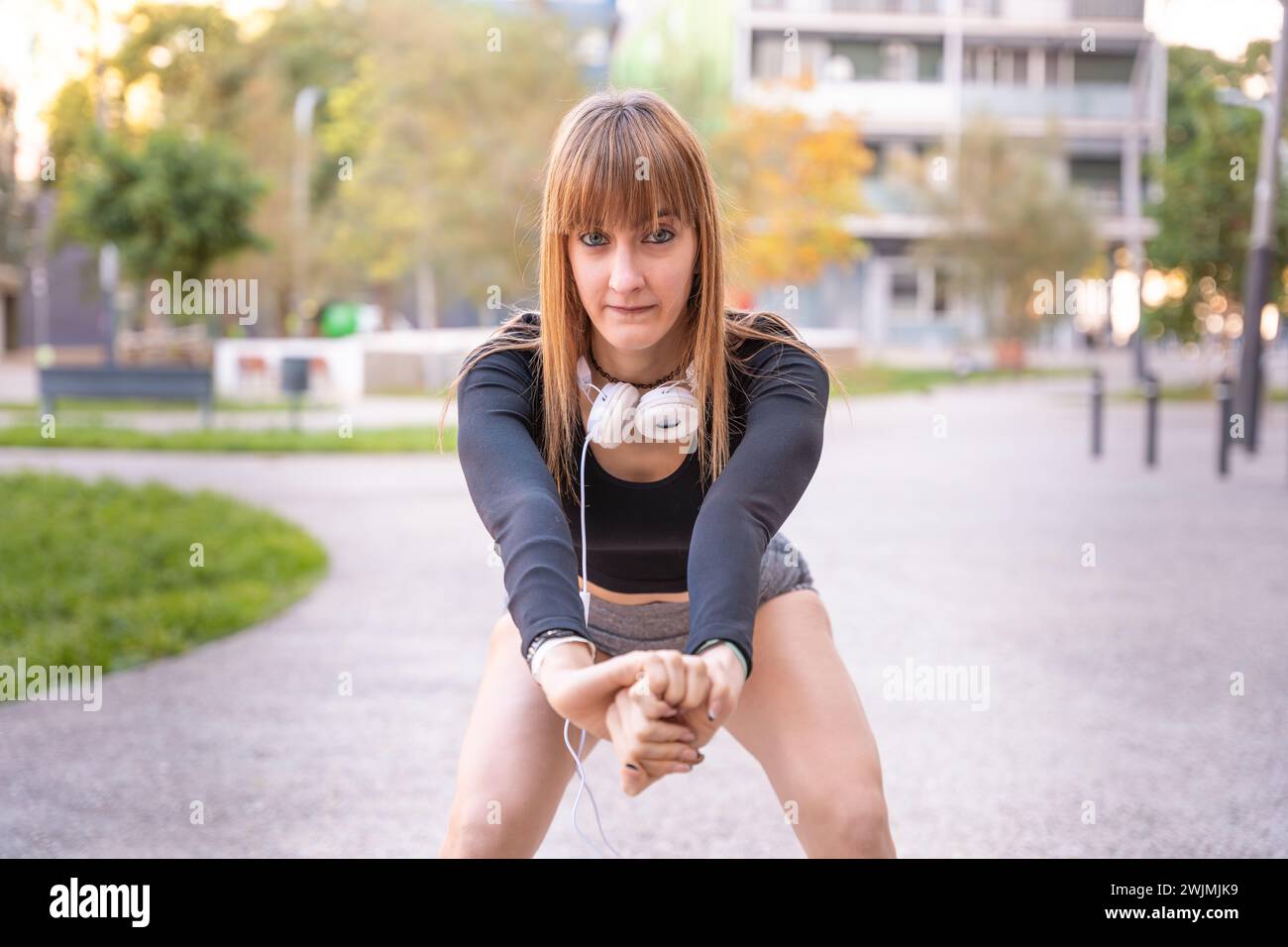 Active and fit female athlete doing squat exercise outdoors. Stock Photo