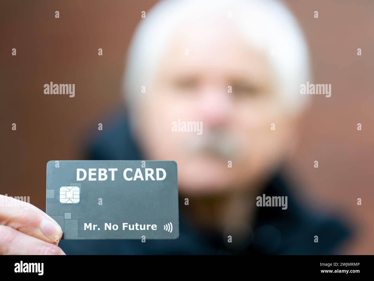 Old ma holds a debit card with the label 'debt card'. Stock Photo