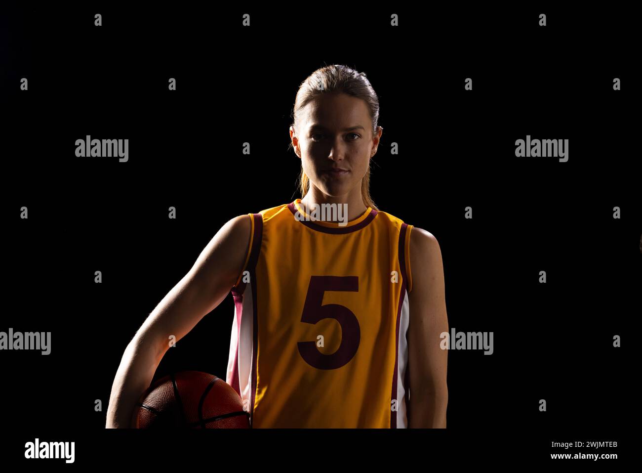 Confident female basketball player showcases determination and skill. Stock Photo