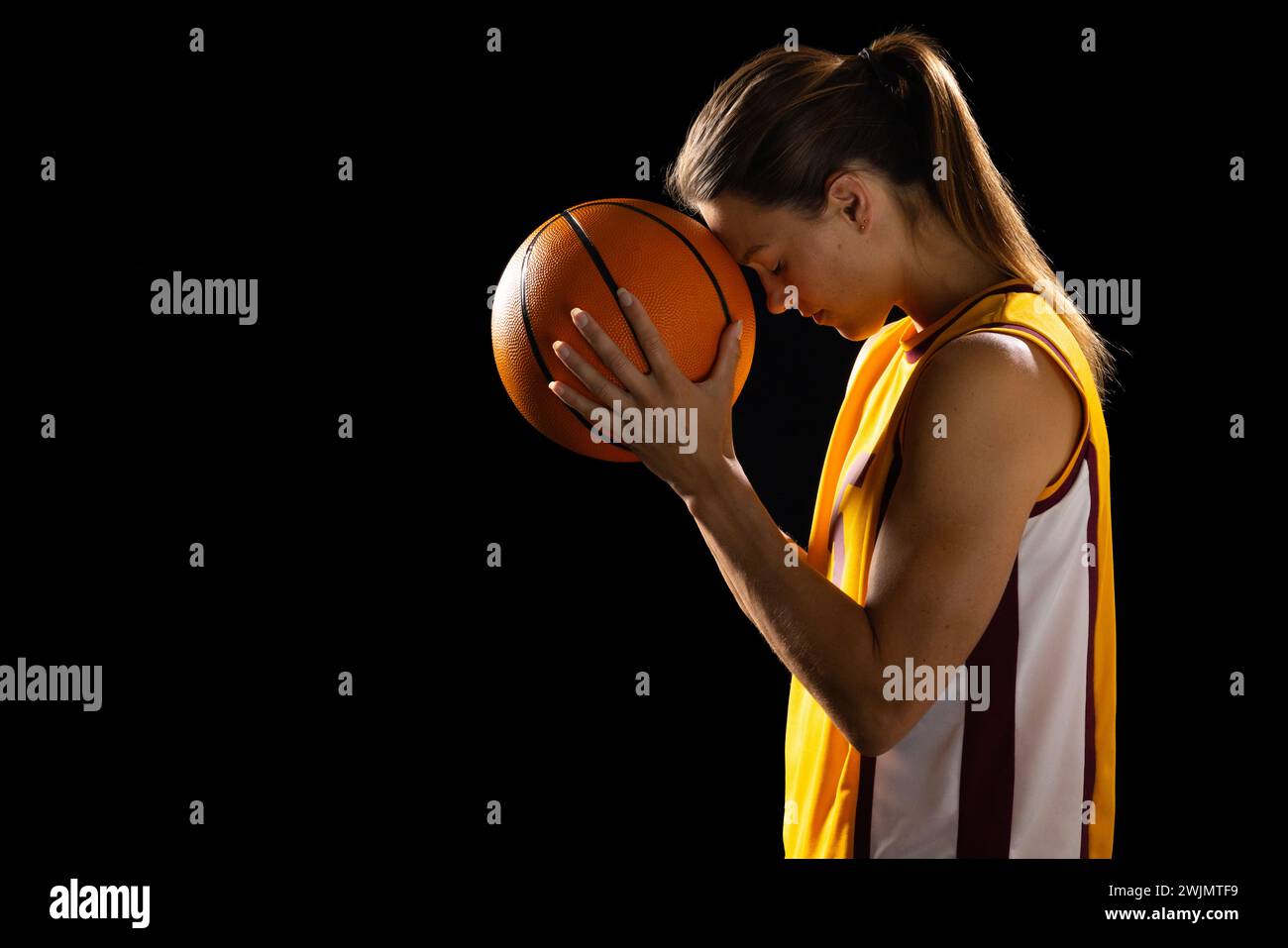 Young female basketball player shows intense focus in studio photo. Stock Photo