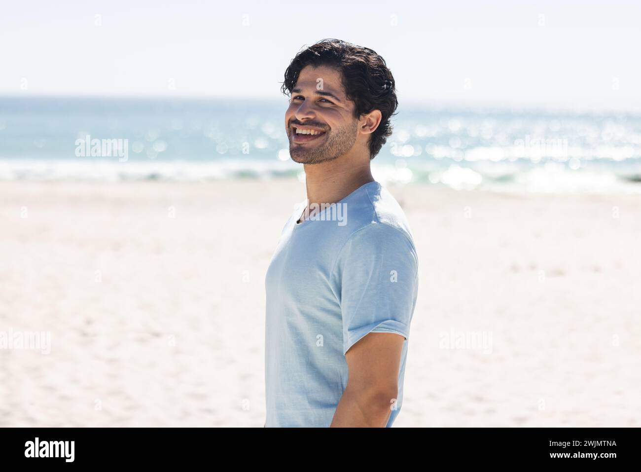 Young biracial man enjoys a sunny day at the beach Stock Photo