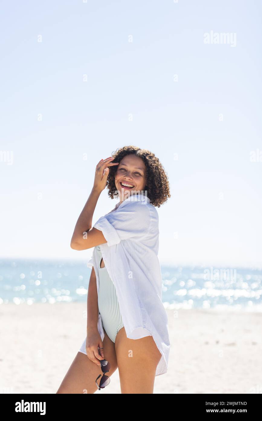 Young biracial woman enjoys a sunny beach day, with copy space unaltered Stock Photo
