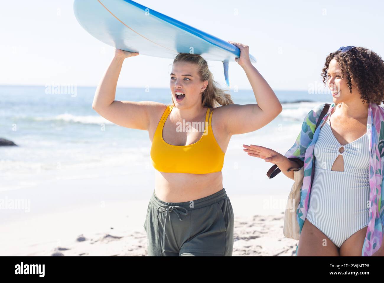Young Caucasian woman and biracial woman enjoy a sunny beach day Stock Photo