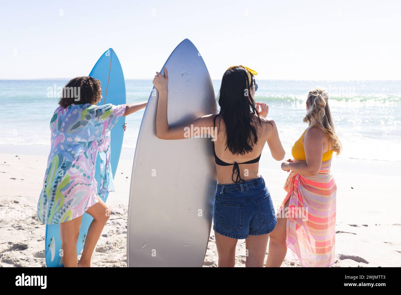 Young biracial and Caucasian women stand by the ocean Stock Photo