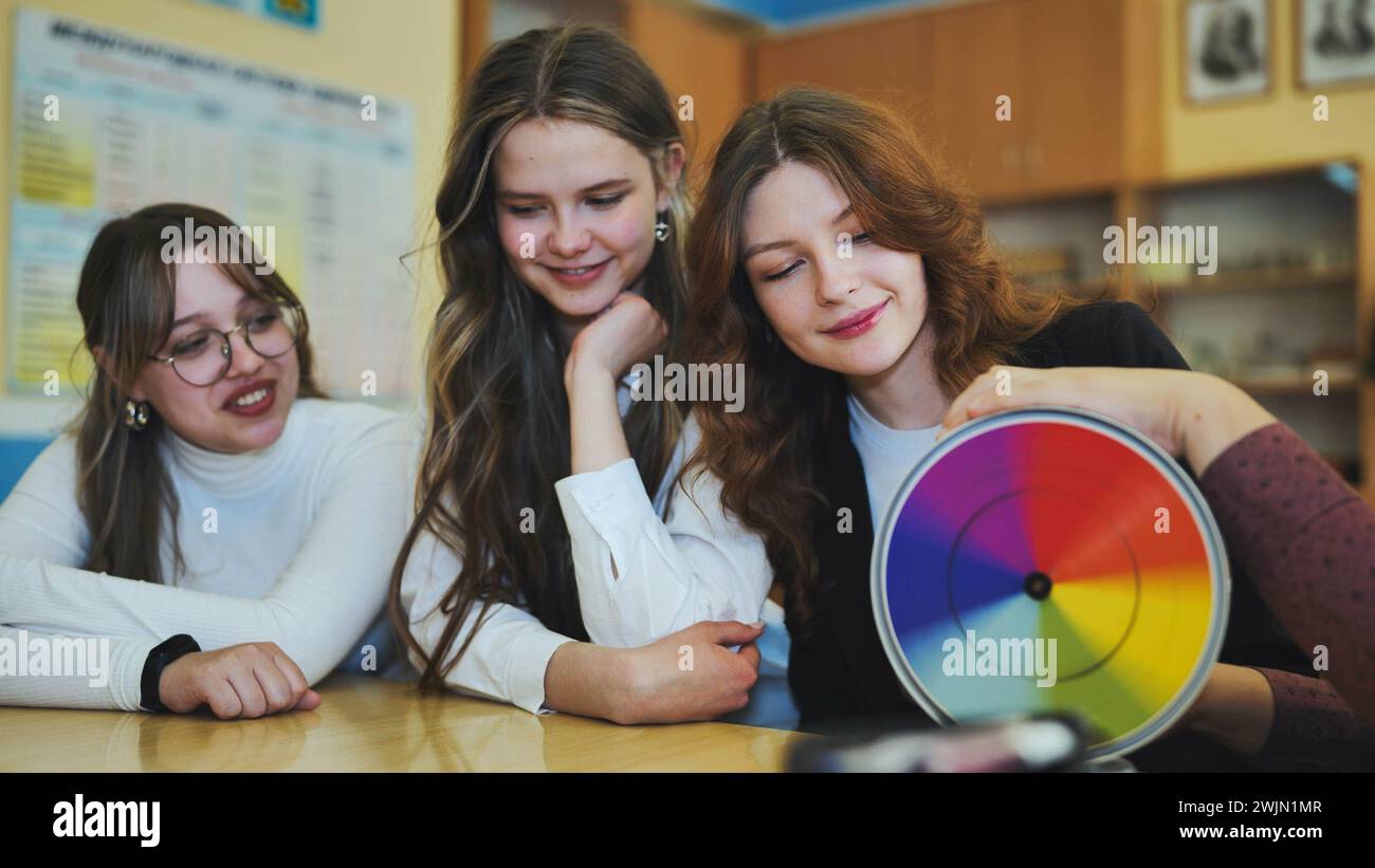 Students in physics class spin Newton's multicolored disk. Stock Photo