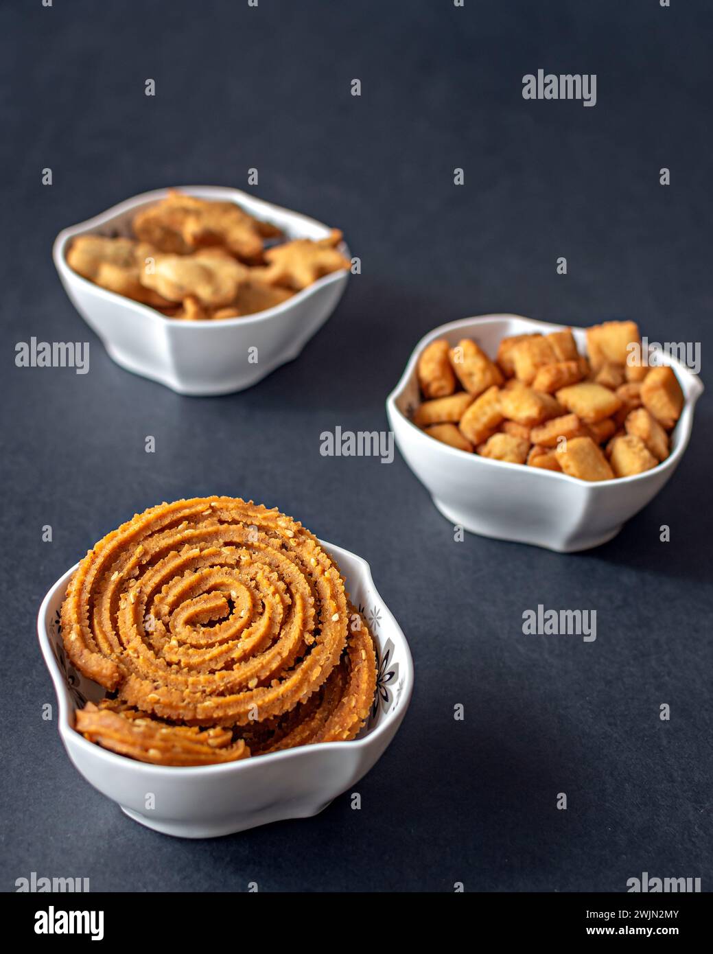 Assorted , fresh Diwali snacks or faral items filled in white bowls with a clear black background. Stock Photo