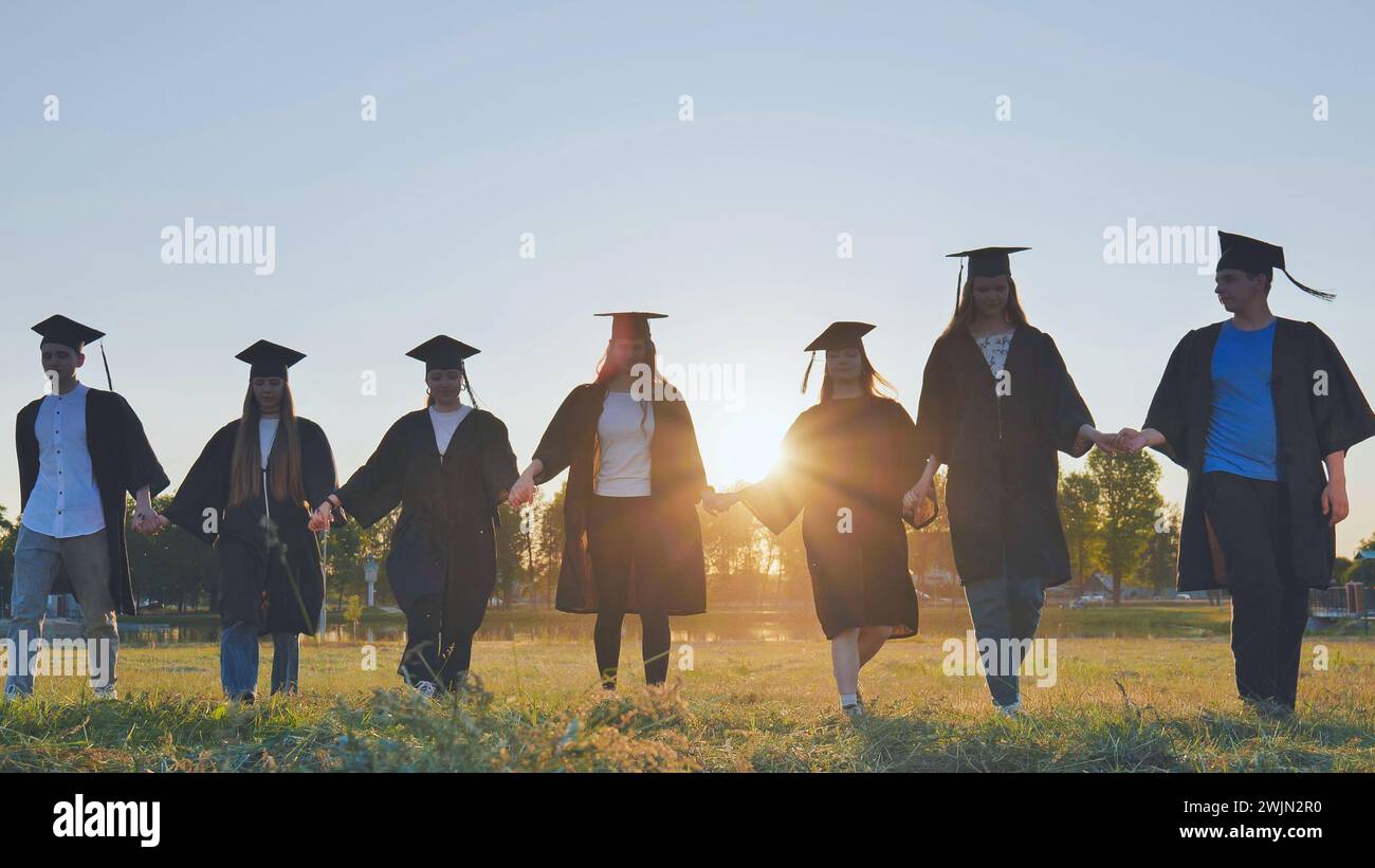 Graduate students walking through an evening meadow at sunset. Stock Photo
