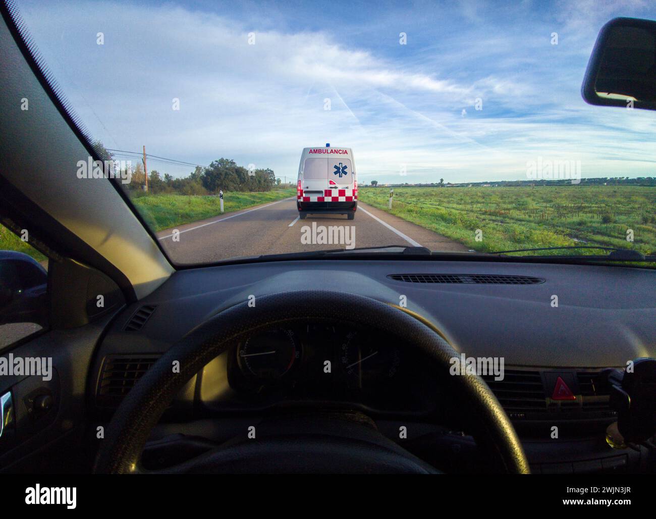 Driving behind an ambulance on local road. View from the inside of the car. View from the inside of the car Stock Photo