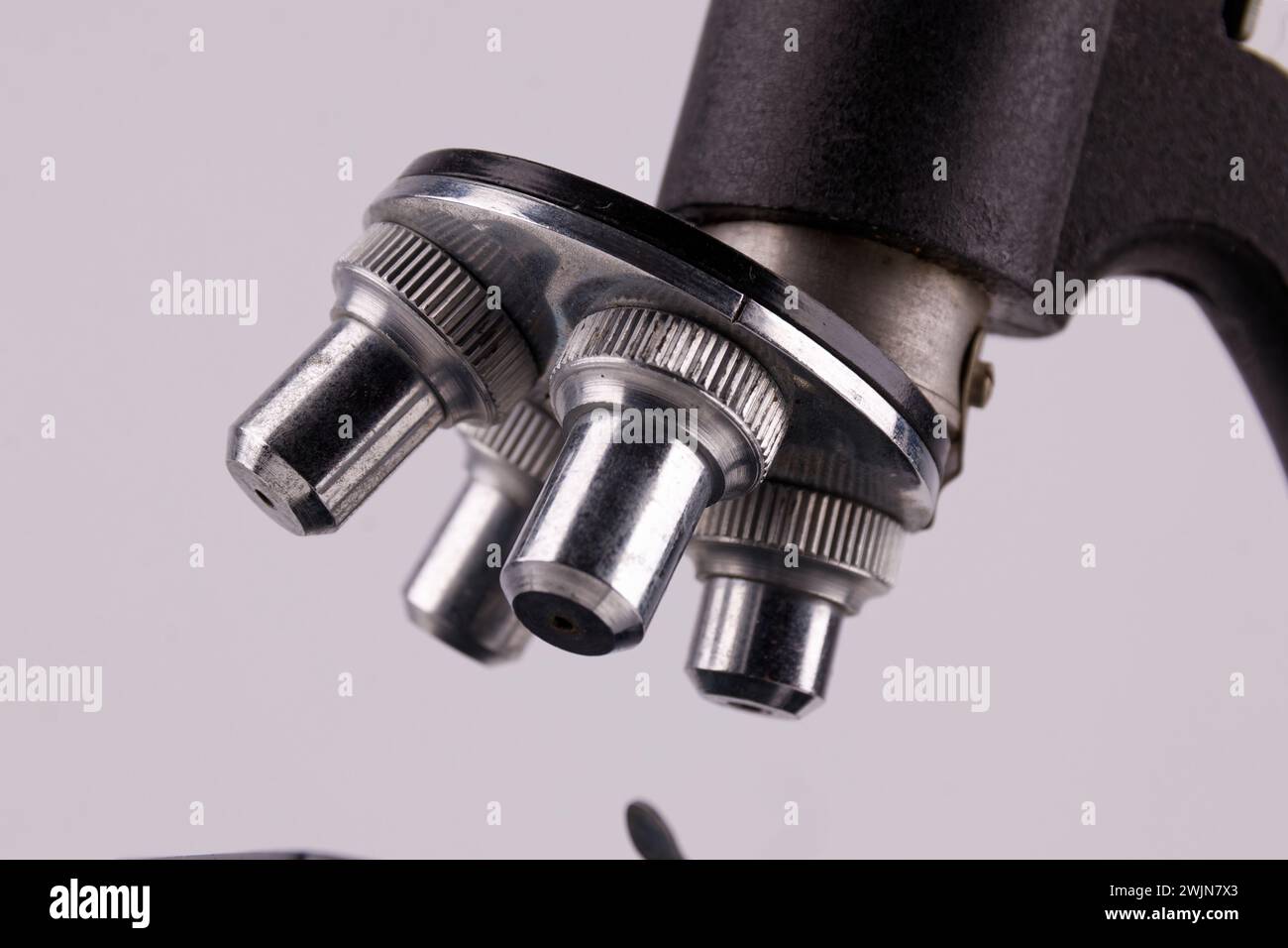 an old microscope stands on a white surface with real shadows, close up Stock Photo