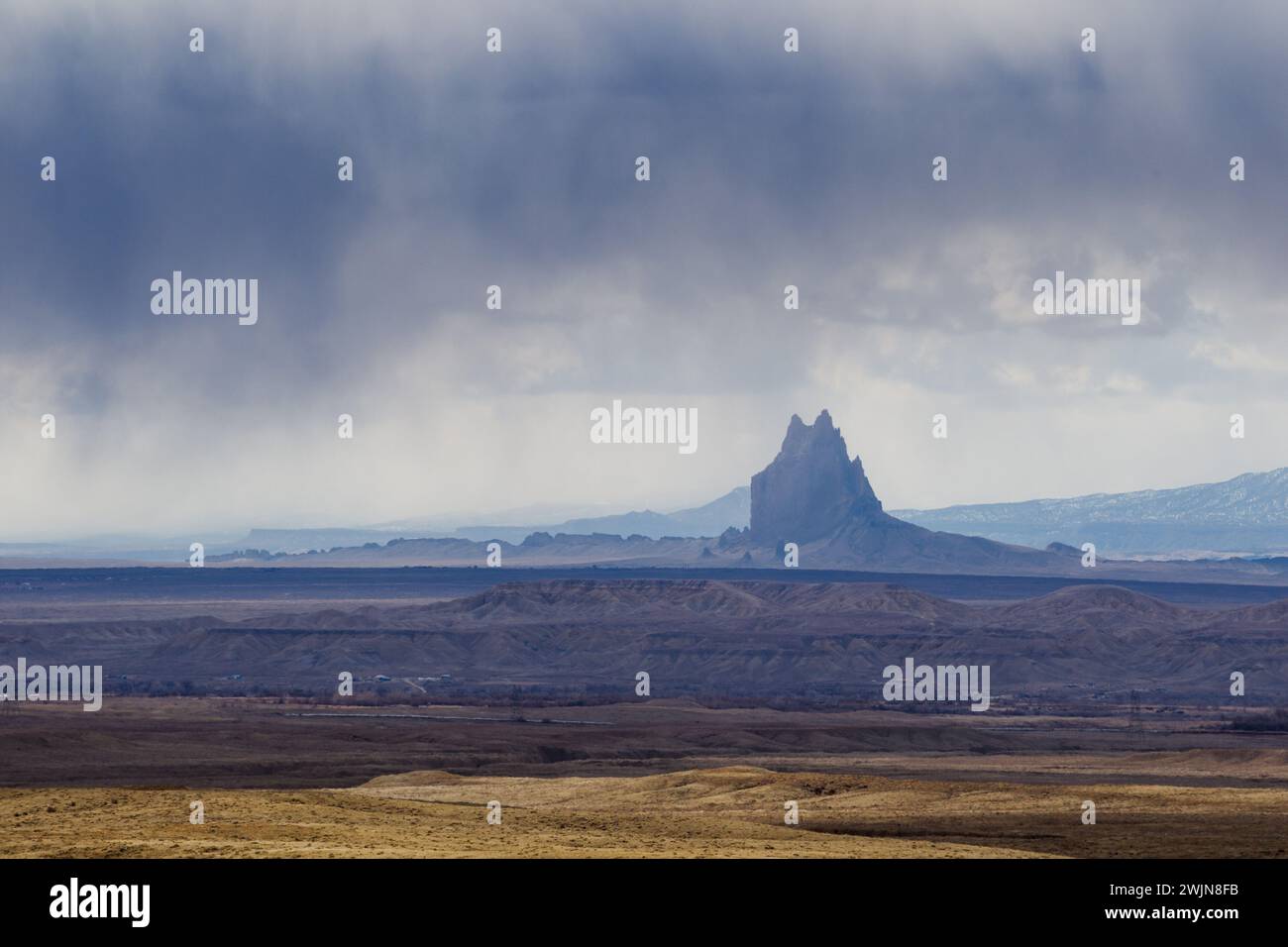 Shiprock is a volcanic basalt monolith on the Navajo Reservation near the town of Shiprock, New Mexico.  Virga is the name for these streaks of rain t Stock Photo