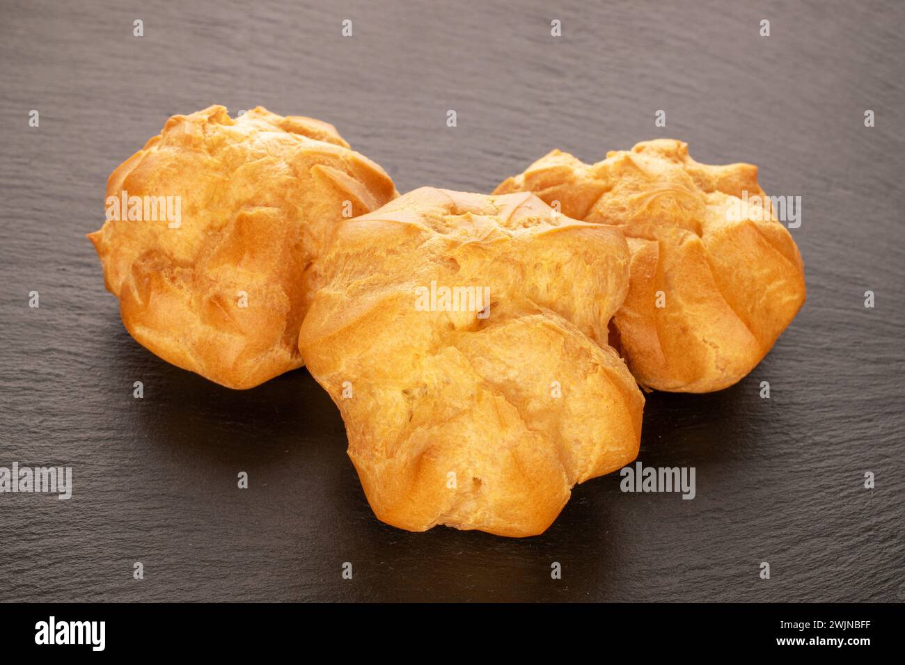 Three delicious éclairs on slate stone, macro. Stock Photo