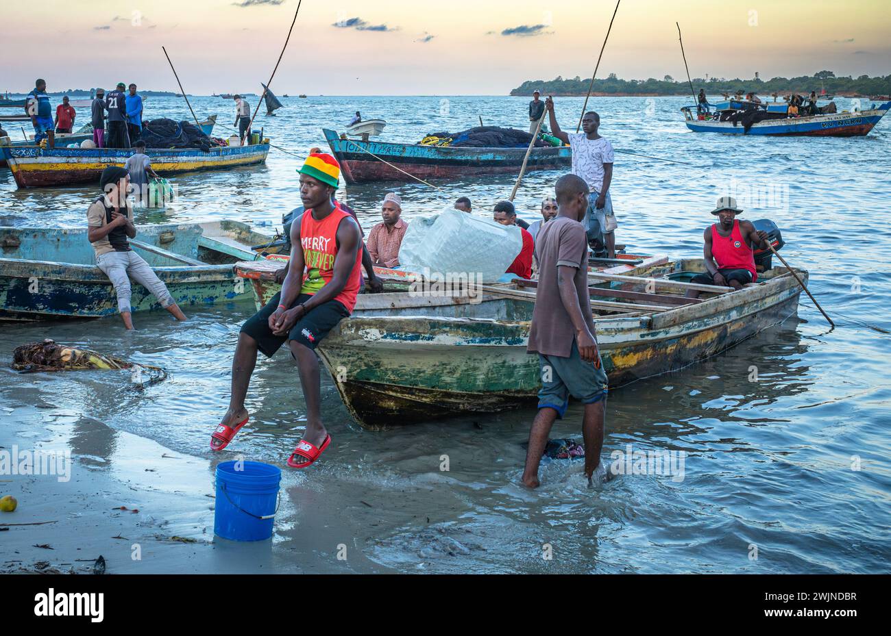 Fishermen wait with their traditional wooden dhow boat in the evening at Kivukoni Fish Market, Dar es Salaam, Tanzania, Stock Photo