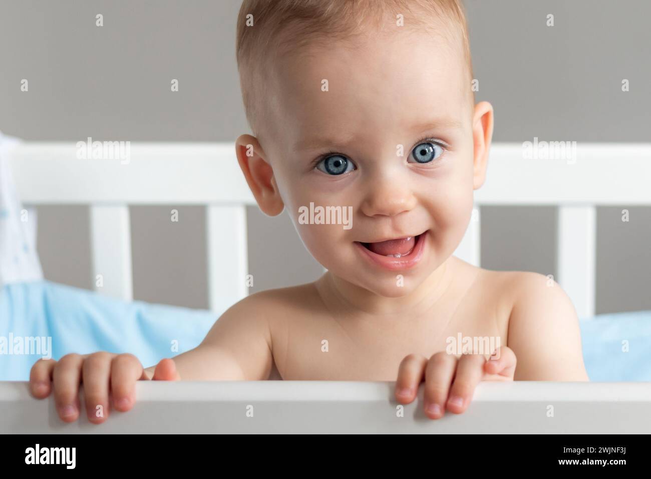 One year old baby standing in a crib smiling Stock Photo - Alamy