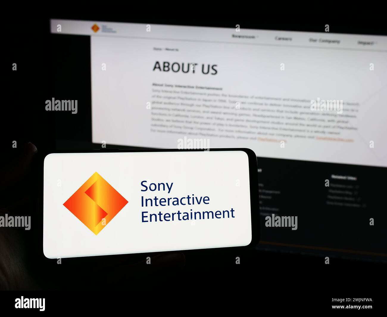 Person holding smartphone with logo of US video game company Sony Interactive Entertainment LLC in front of website. Focus on phone display. Stock Photo