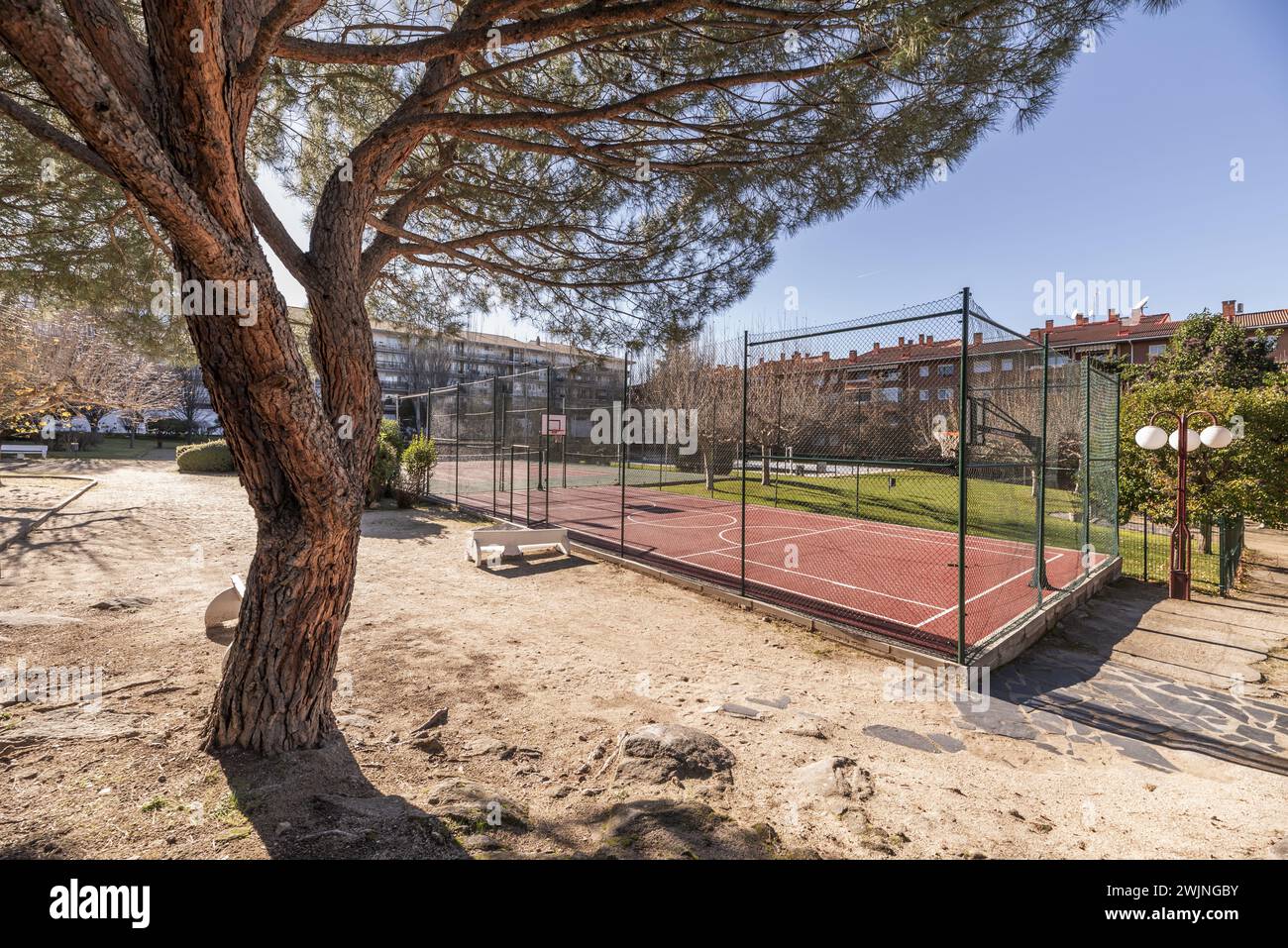 A basketball court with a perimeter metal fence within a plot of common areas in a community Stock Photo