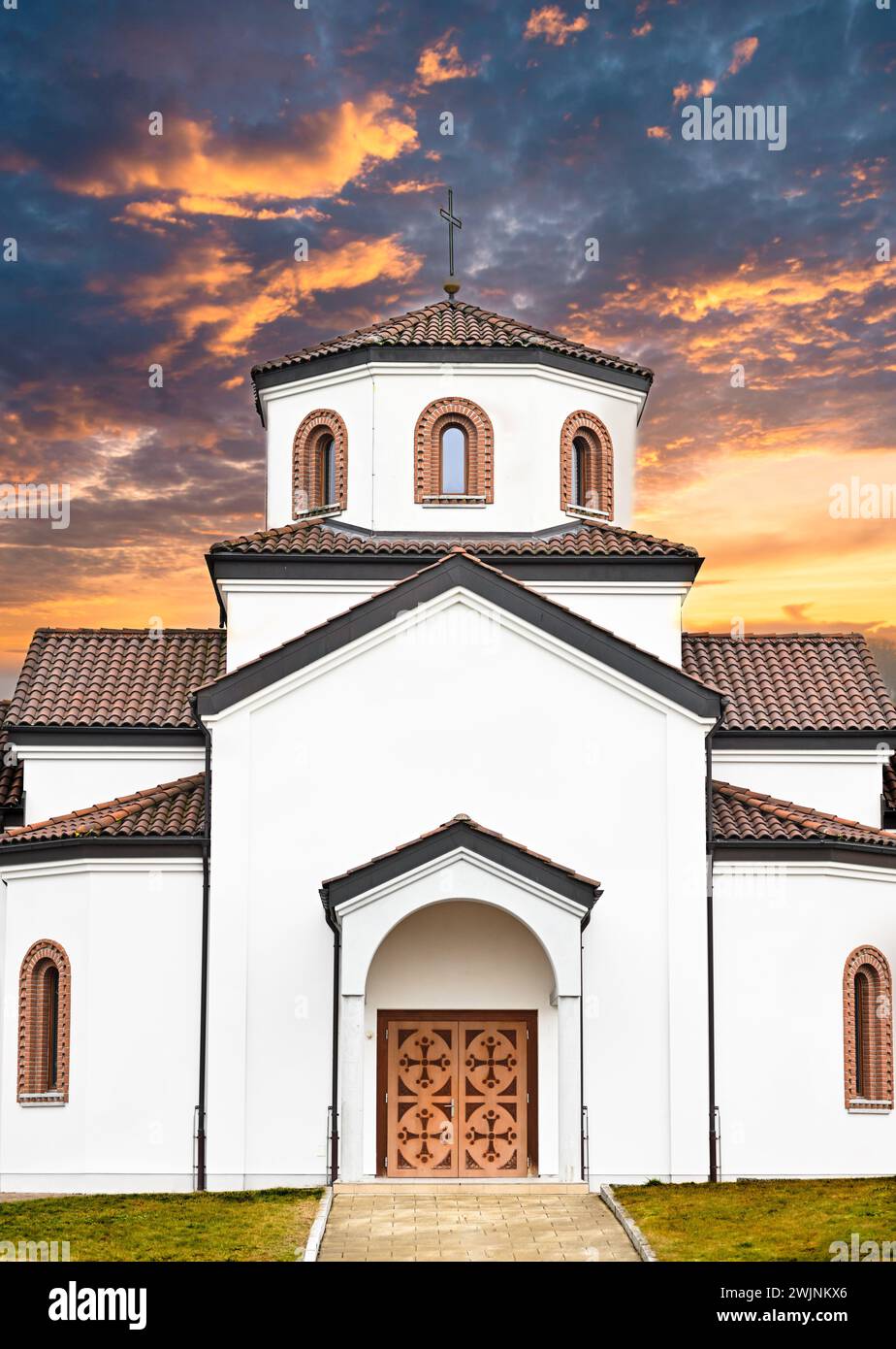 A church at sunset with prominent bell tower and arched entrances Stock Photo