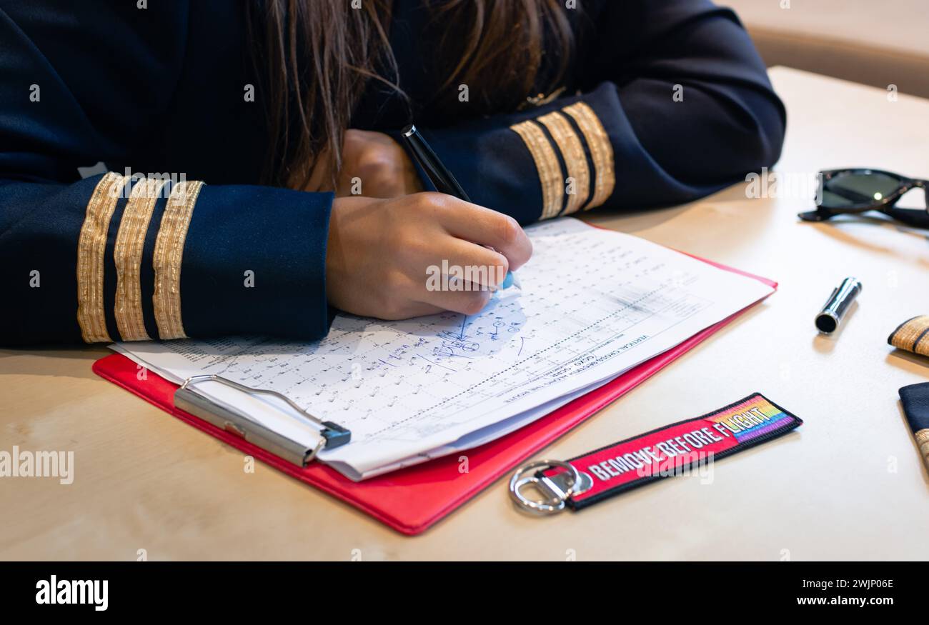 Unrecognizable female pilot preparing flight documentation with a Remove Before Flight keychain. High quality photo Stock Photo