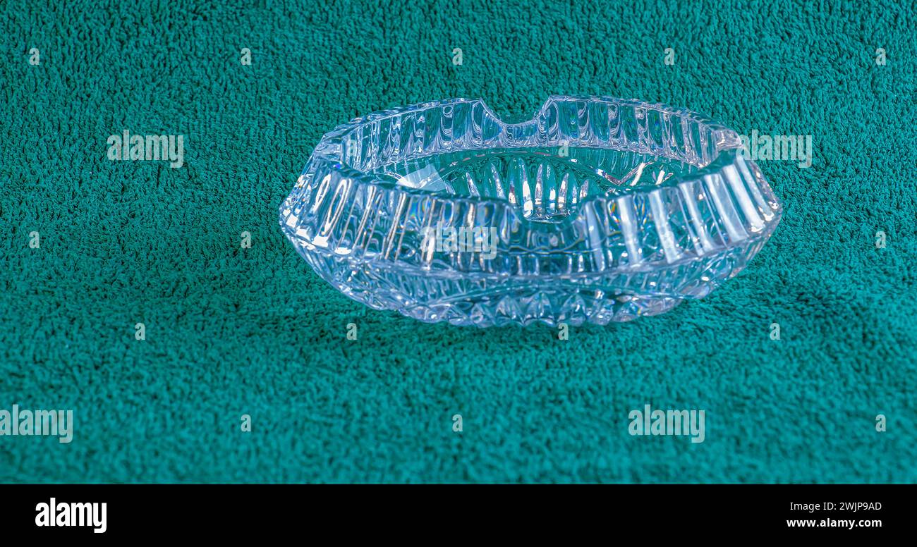 Empty crystal ashtray on green background. The ashtray was made in the mid-20th century. Stock Photo