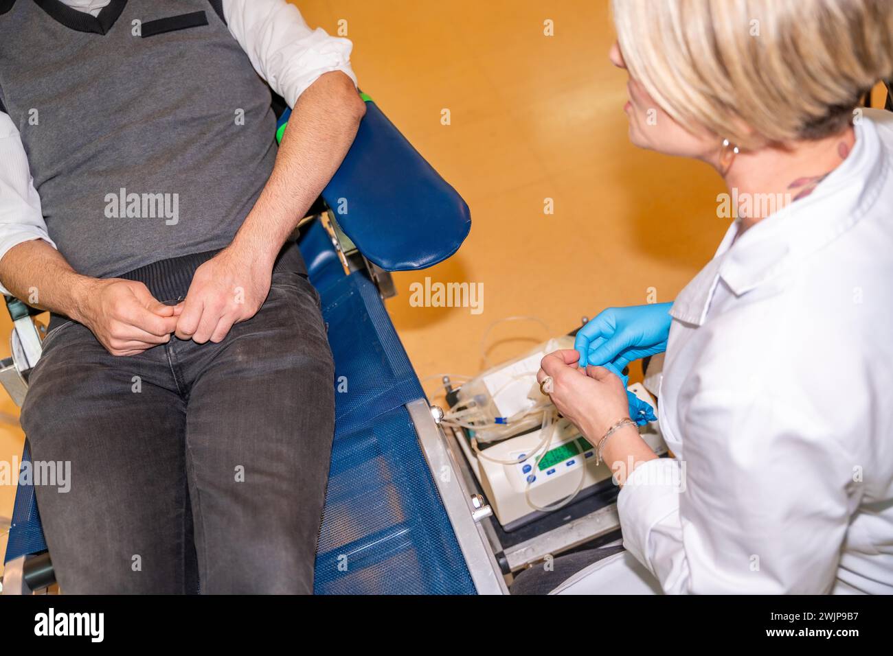 Top view close-up of a female nurse preparing the material for a blood donation next to a volunteer sitting in a chair Stock Photo