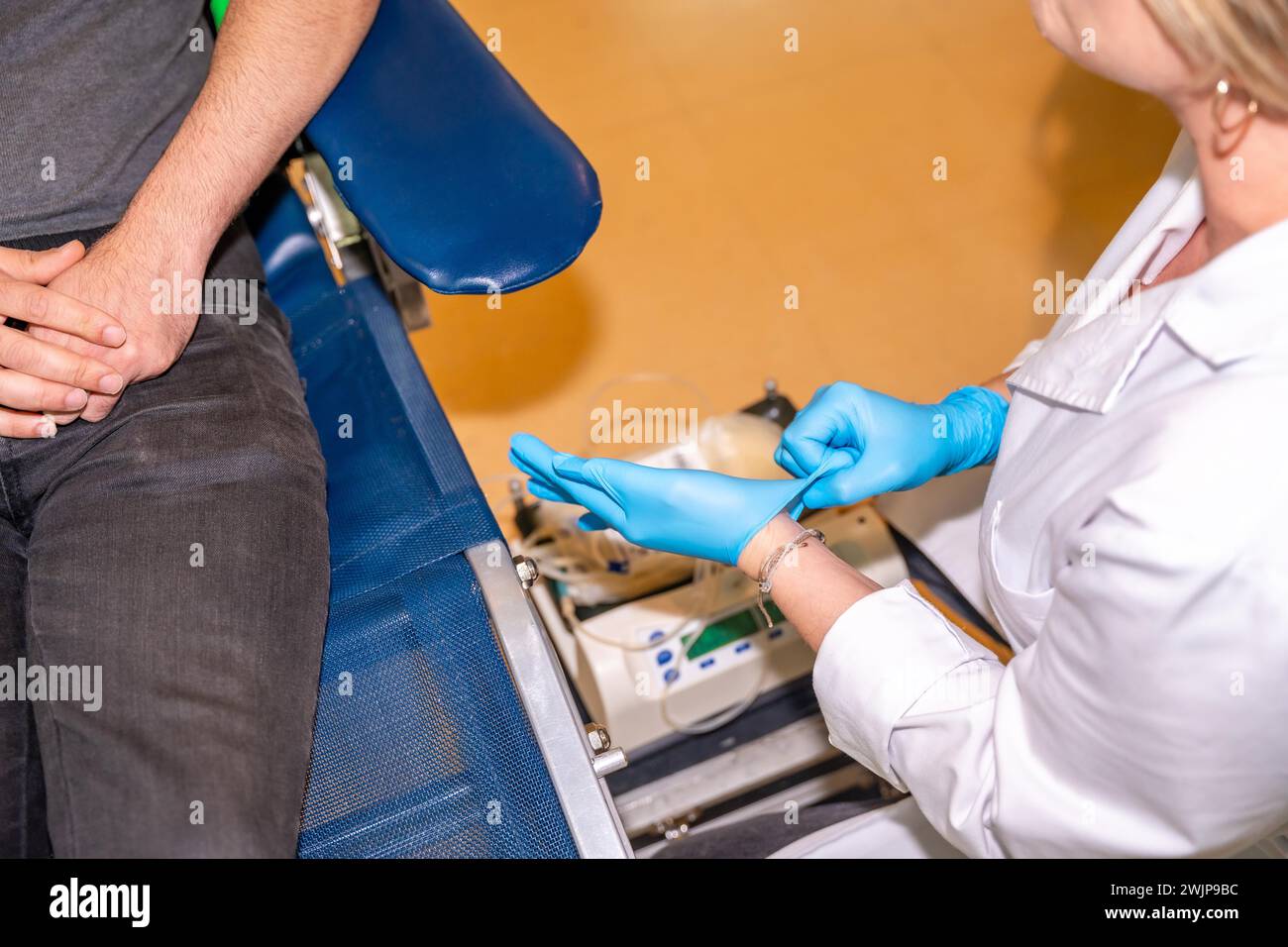 Unrecognizable nurse in lab coat putting on surgical gloves getting