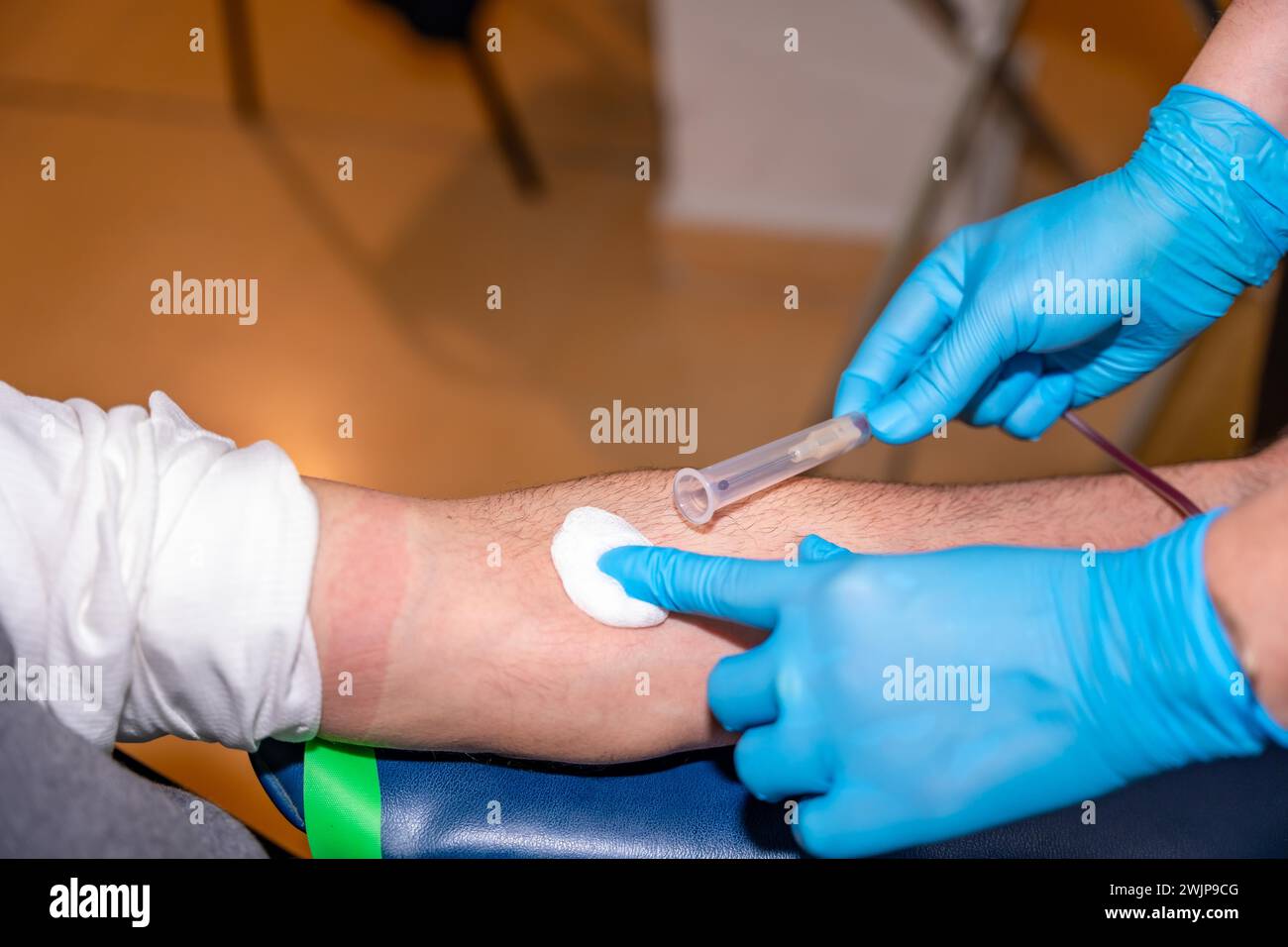 Nurse extracting needle from arm and cleaning the area in a man donating blood Stock Photo