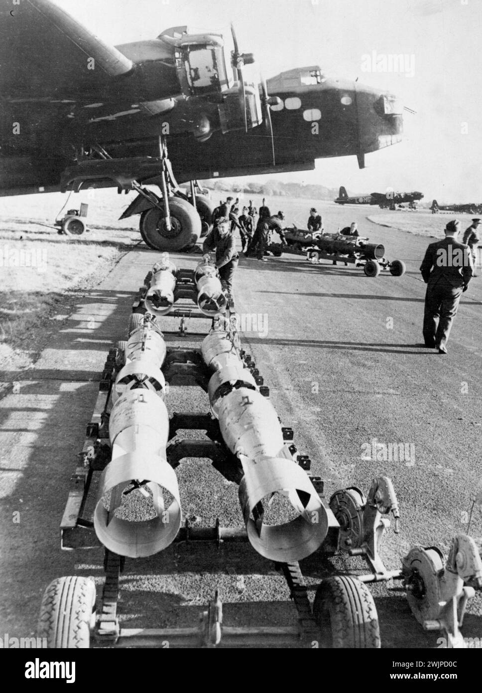 Loading A British Bomber -- A long line of bombs is snaked under the nose of a Stirling bomber in an Raf station somewhere in England. The bombs are hoisted into the racks by motor power and the plane is Credited with being Capable of carrying from three to nine times more bombs than other English bombing planes. British sources said the plane was being loaded for a raid on Germany. October 18, 1941. (Photo by Associated Press Photo). Stock Photo