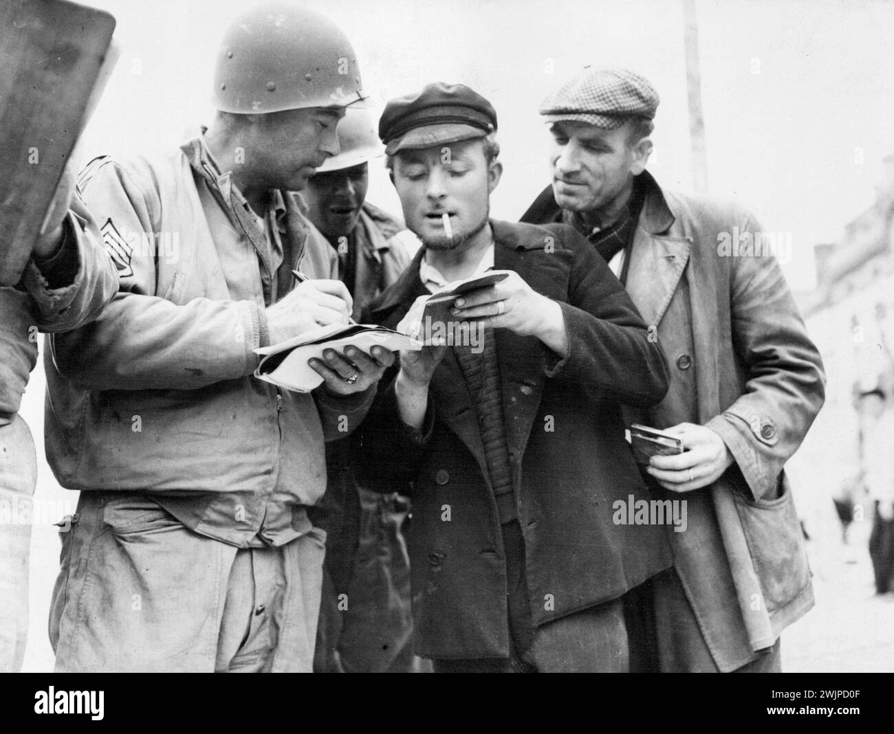 French civilians work for Allies -- A French civilian shows his identification papers to an American soldier as he signs on for work to help repair roads and clear up areas in Cherbourg. Allied repair crews follow behind the armies as the Nazis are driven from Normandy. September 18, 1944. (Photo by New York Times Photo). Stock Photo