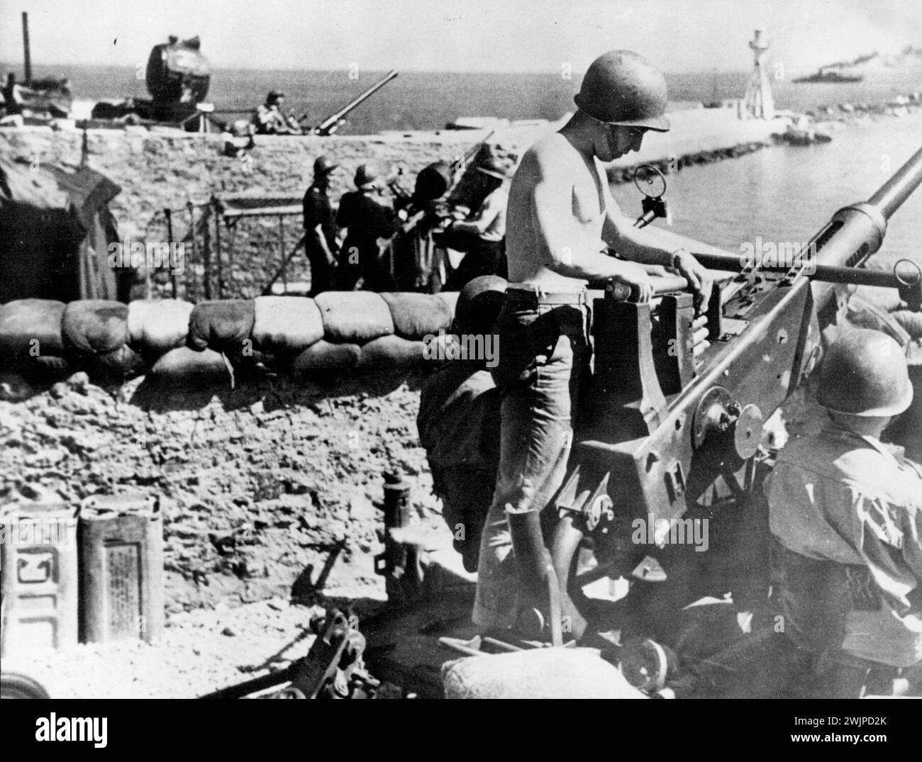Gunners From Three Nations Protect Harbour In North Africa -- The unity of the United Nations is illustrated in this picture of three anti-aircraft batteries protecting - a worth African harbor. In the foreground is an American crew manning a Bofors gun. Beyond the sandbags, French anti-aircraft artillerymen stand by an Oerlikon gun while in the background a British crew mans another Bofors. January 1, 1943. Stock Photo
