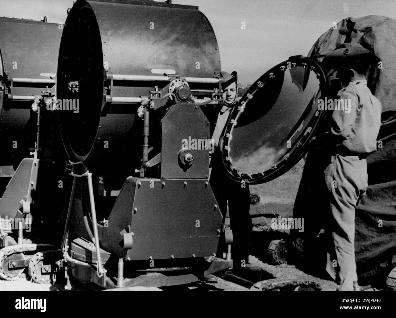 These are the searchlights whose beams nightly stab the sky from stations all over Sydney in search of 'enemy raiders.' Militiamen of the 52nd anti-air-craft battery clean their lights in preparation for fresh entertainment for Sydney's million. April 23, 1940. Stock Photo