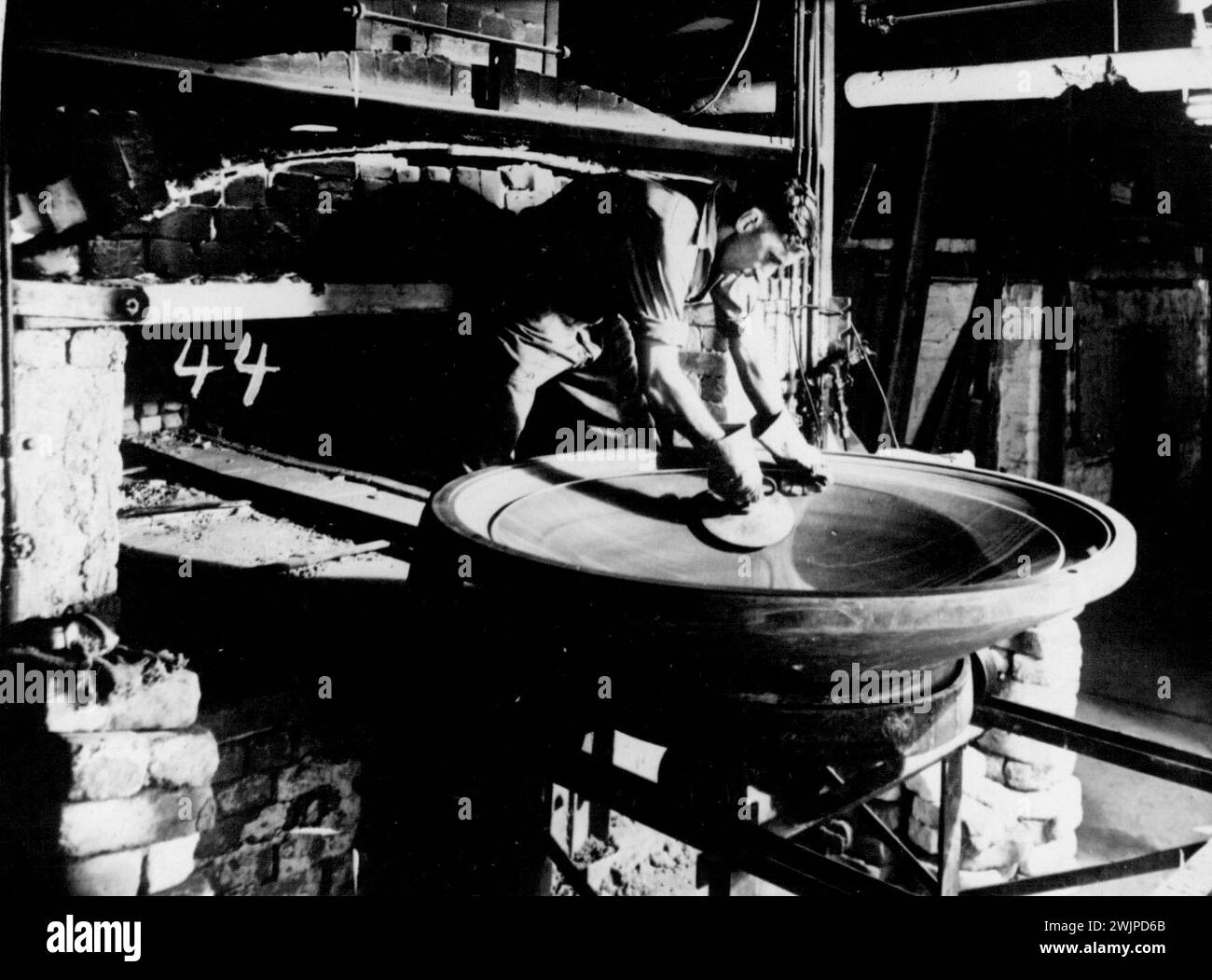 Blast for a parabolic reflector is here being removed from the mould in which it has been cast in an Australian Consolidated Industries annexes. July 14, 1942. Stock Photo