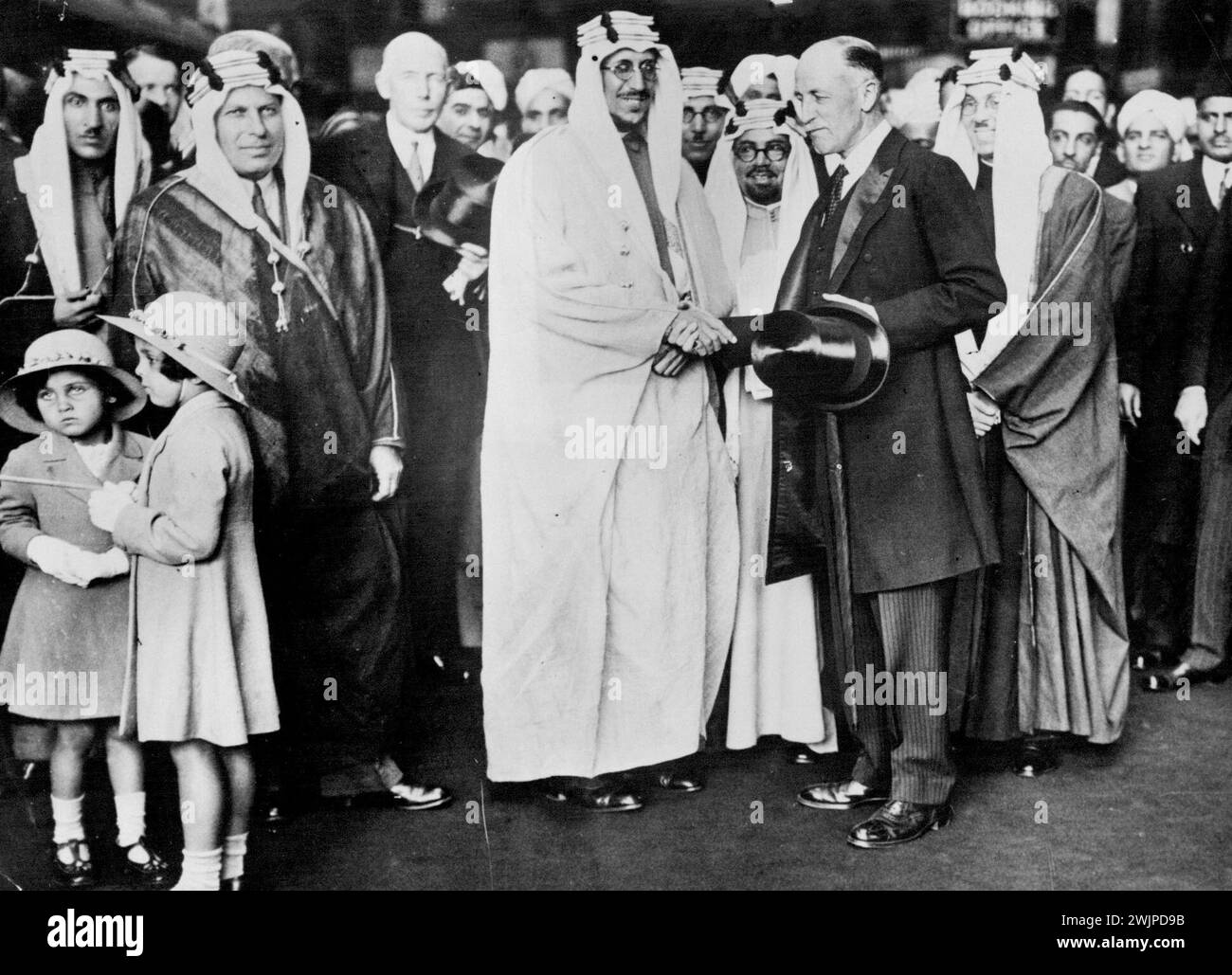 Arabian crown prince arrives in London. The Emir Saud, crown prince of Saudi Arabia, and heir to king Abdul IBN Saud, arriving in England on a visit, June 17th. The crown princes of Saudi Arabia being welcomed on behalf of the king by the Earl of Dunmore on his arrival at Victoria, Station, London. The two little daughters of the Arabian Minister in London may be seen in foreground. June 17, 1935. (Photo by Sports & General Press Agency Limited). Stock Photo