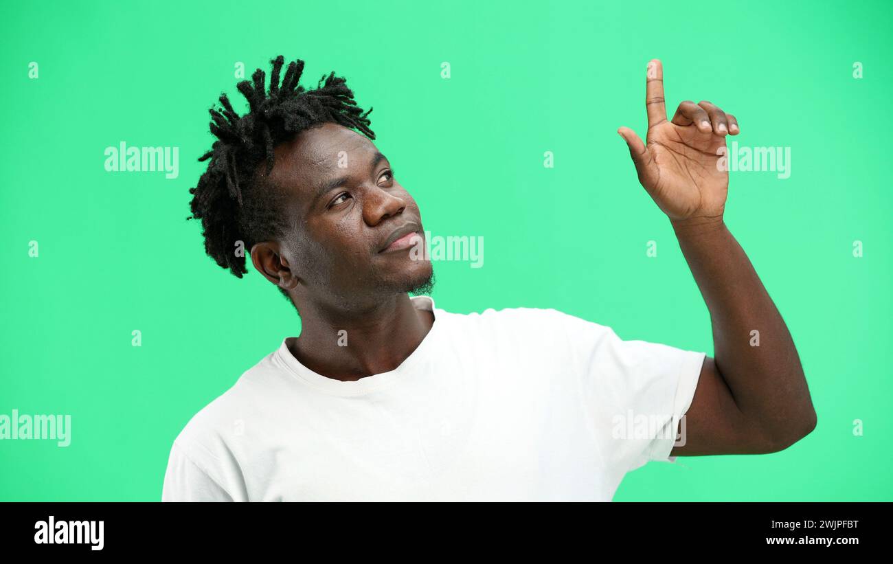 Man, close-up, on a green background, pointing up. Stock Photo