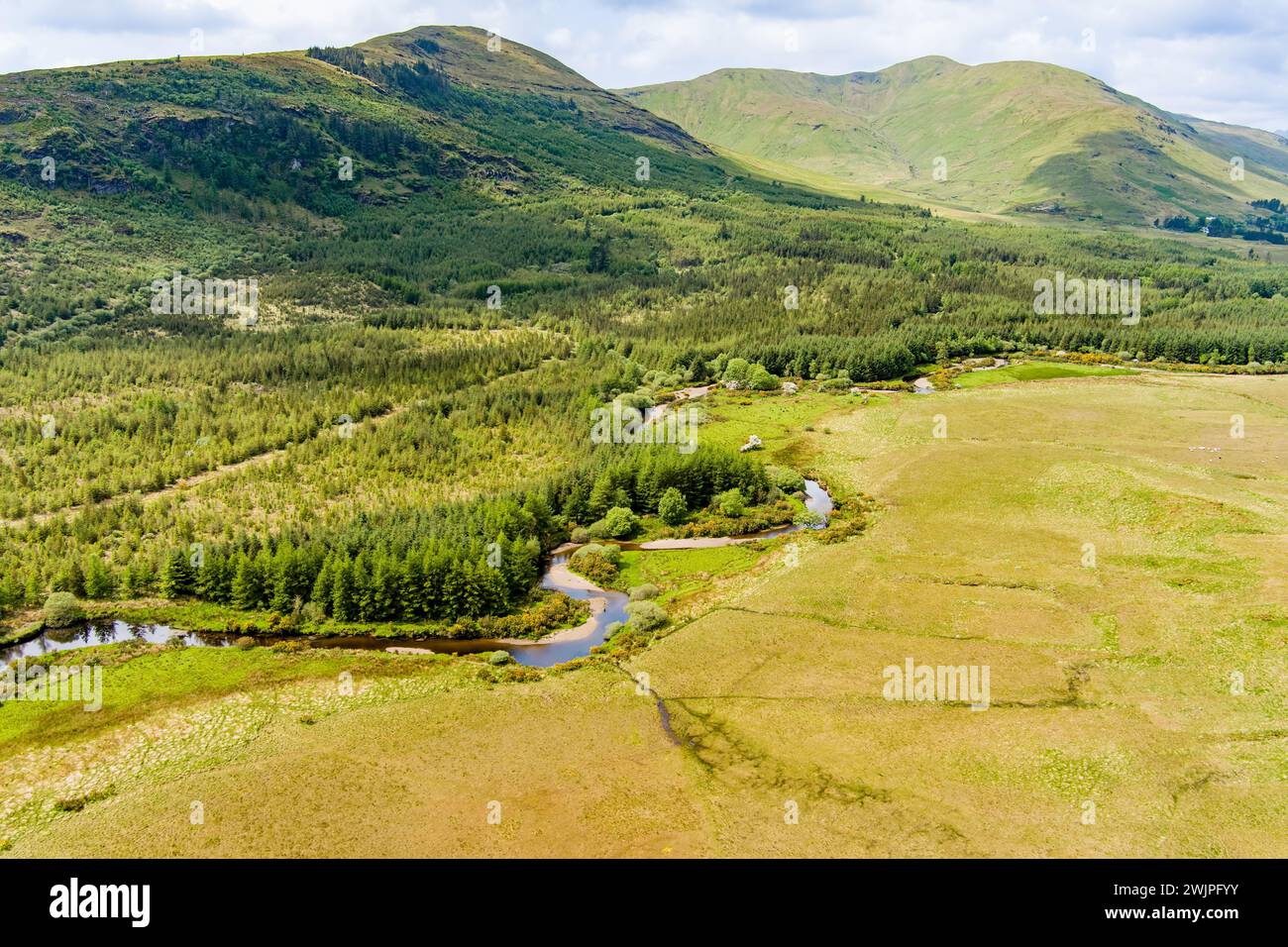 Aerial view of Joyce's river winding down below in Connemara region in Ireland. Scenic Irish countryside landscape with magnificent mountains on the h Stock Photo