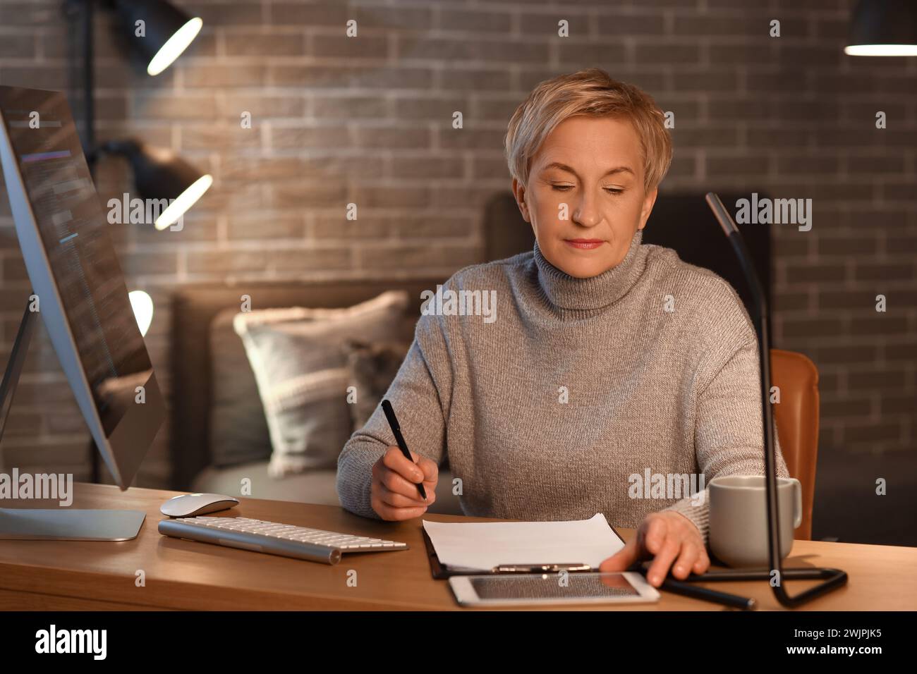 Mature female programmer working in office at night Stock Photo