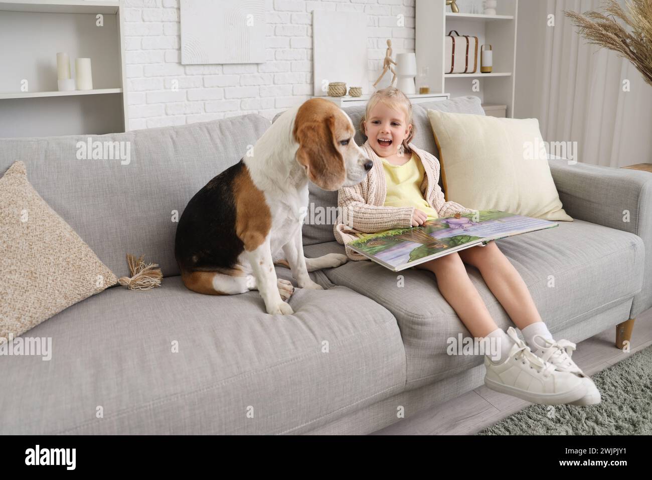 Cute little girl with Beagle dog reading book at home Stock Photo - Alamy